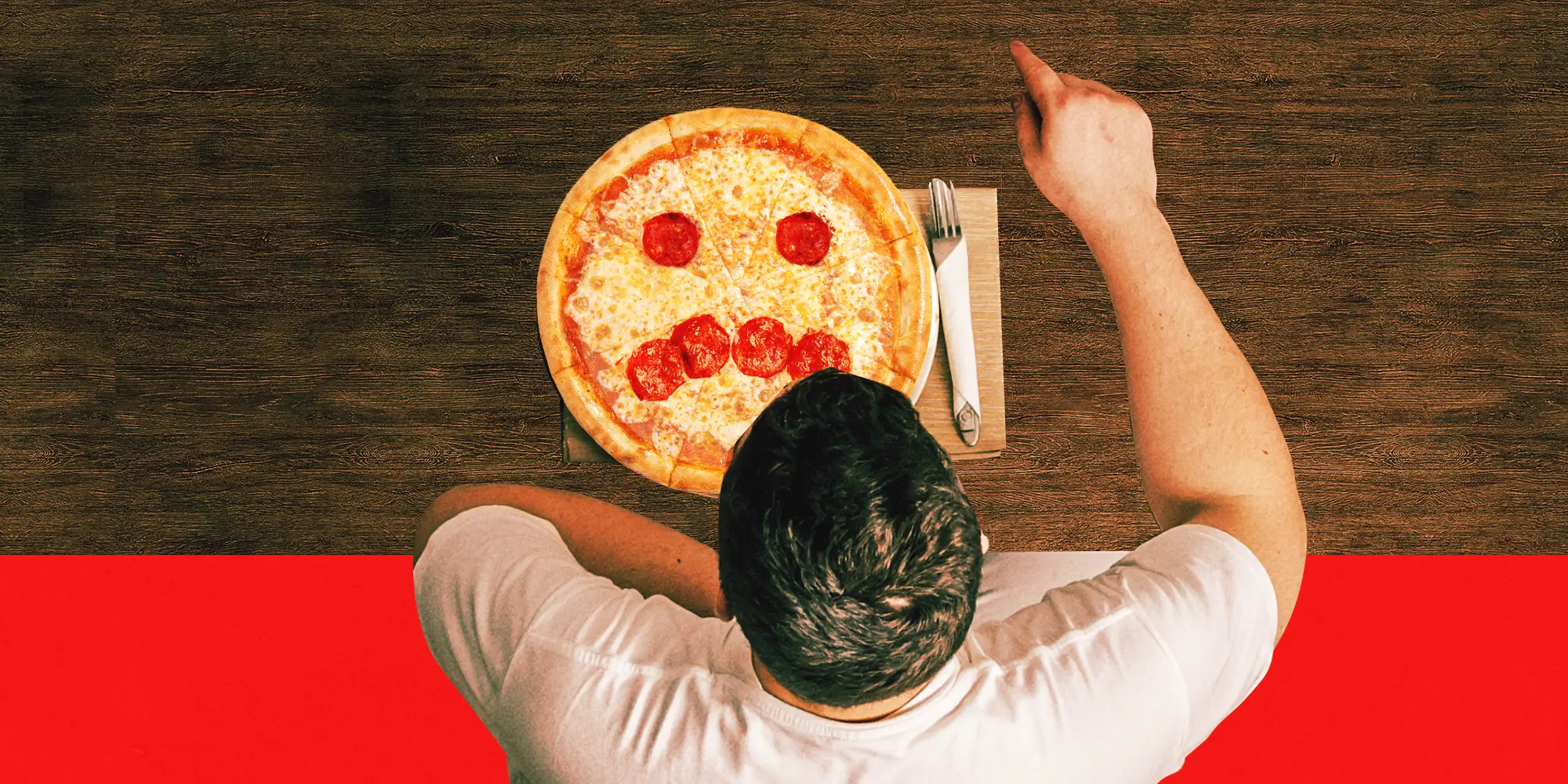 Overhead view of a person seated at a table with a pizza arranged like a frowning face.