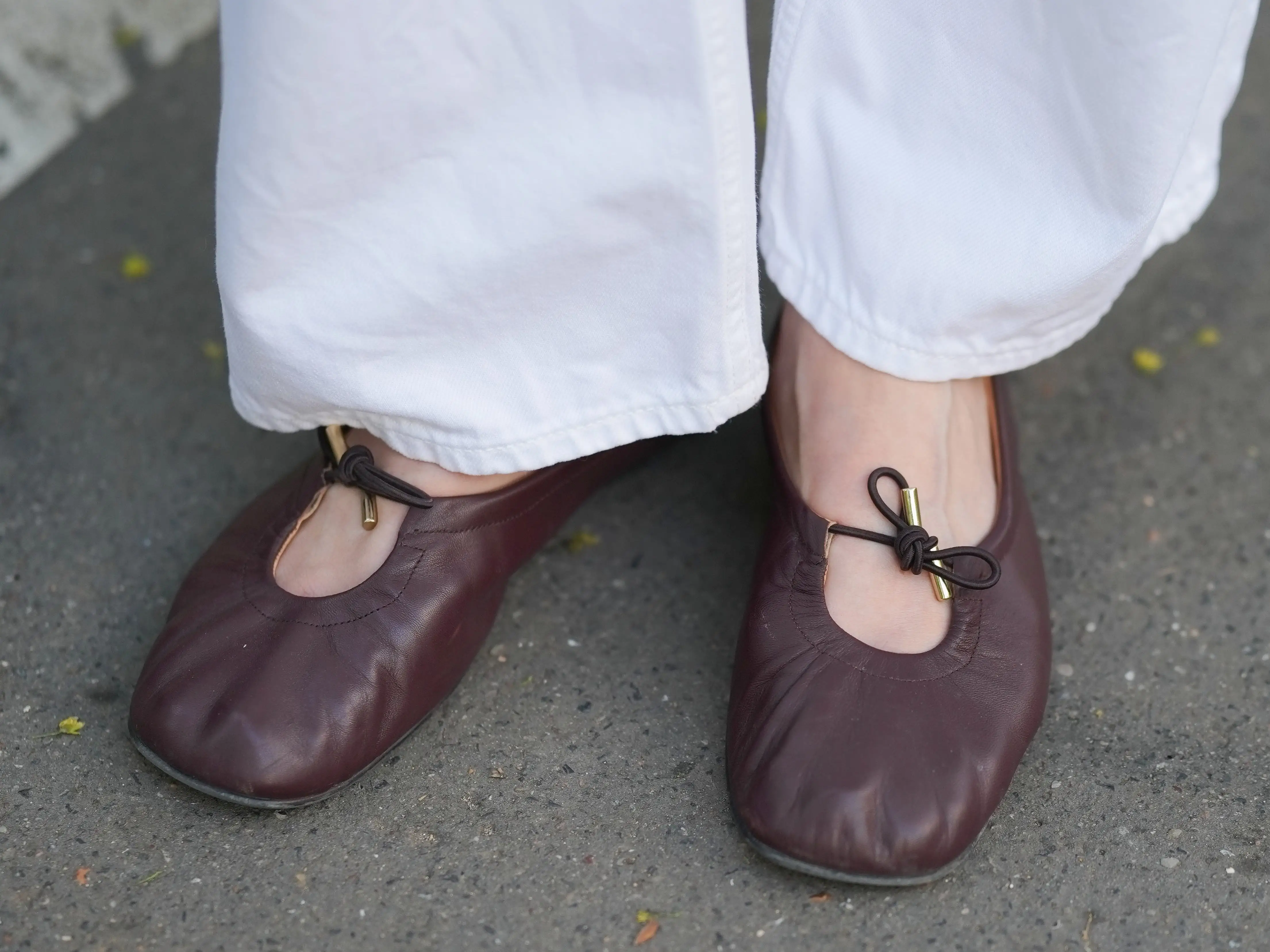 A woman wearing a pair of brown ballet flats.