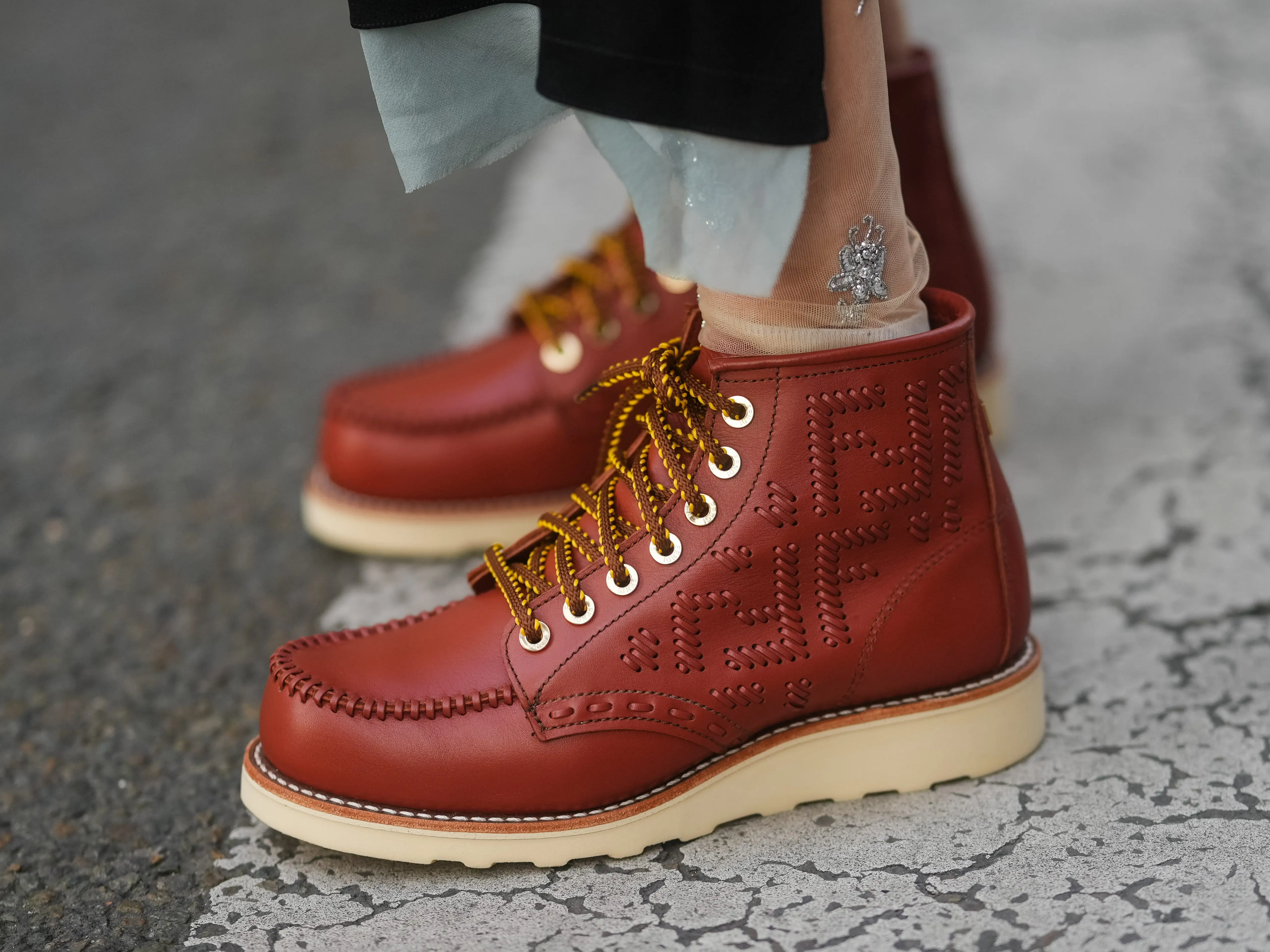 A pair of rust-colored leather boots with hiking-style laces and white rubber soles.