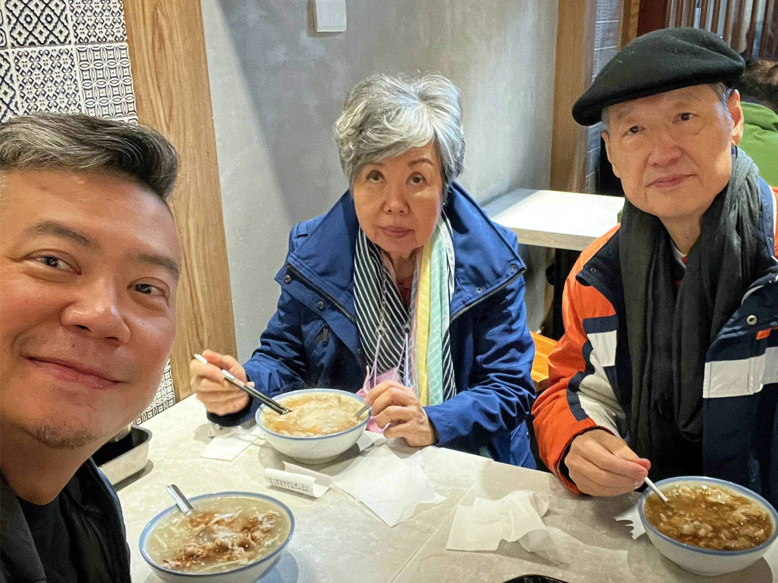 A photo of a man and his parents in a restaurant.
