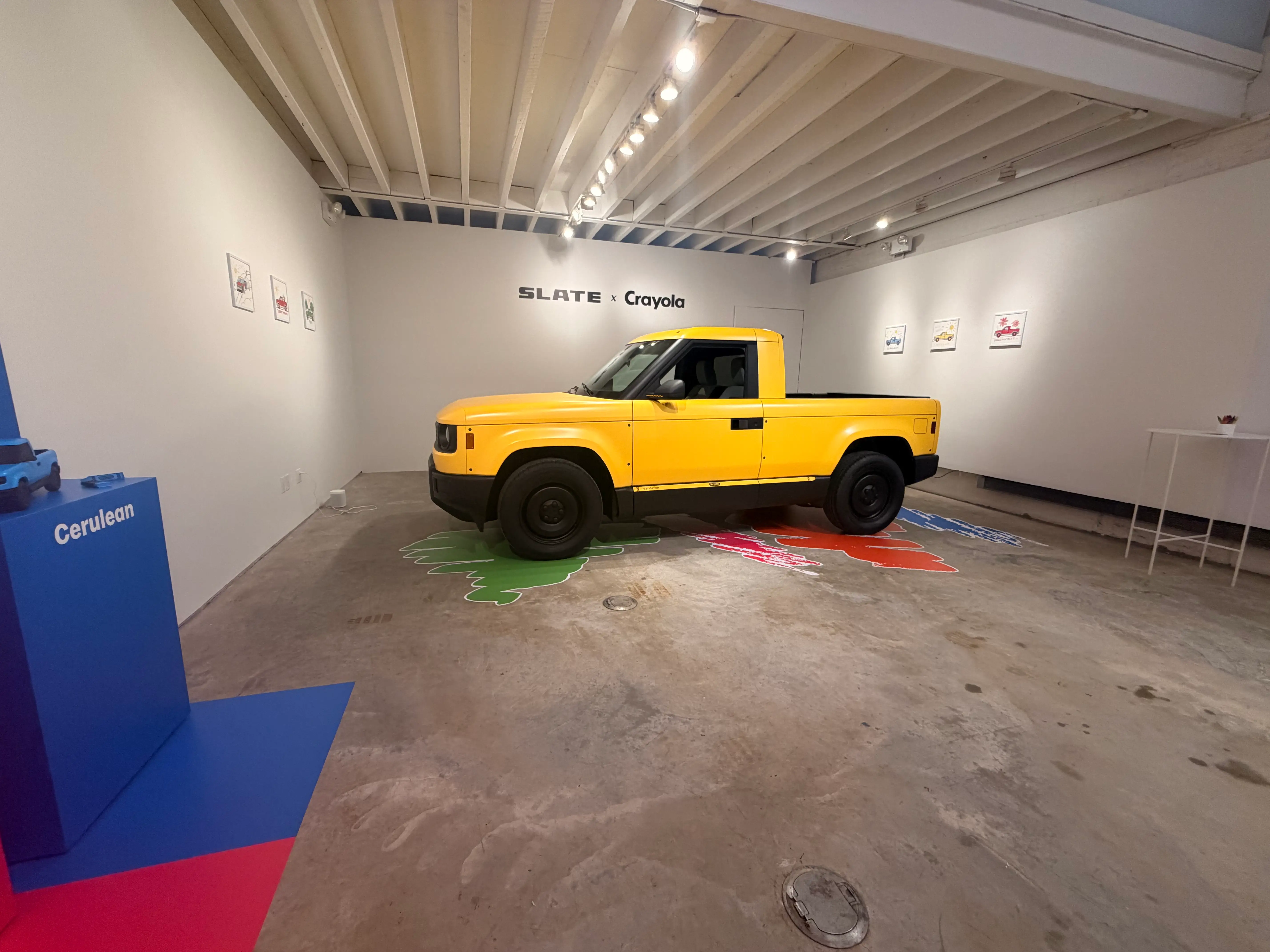 A yellow-wrapped slate truck is parked on a showroom floor.