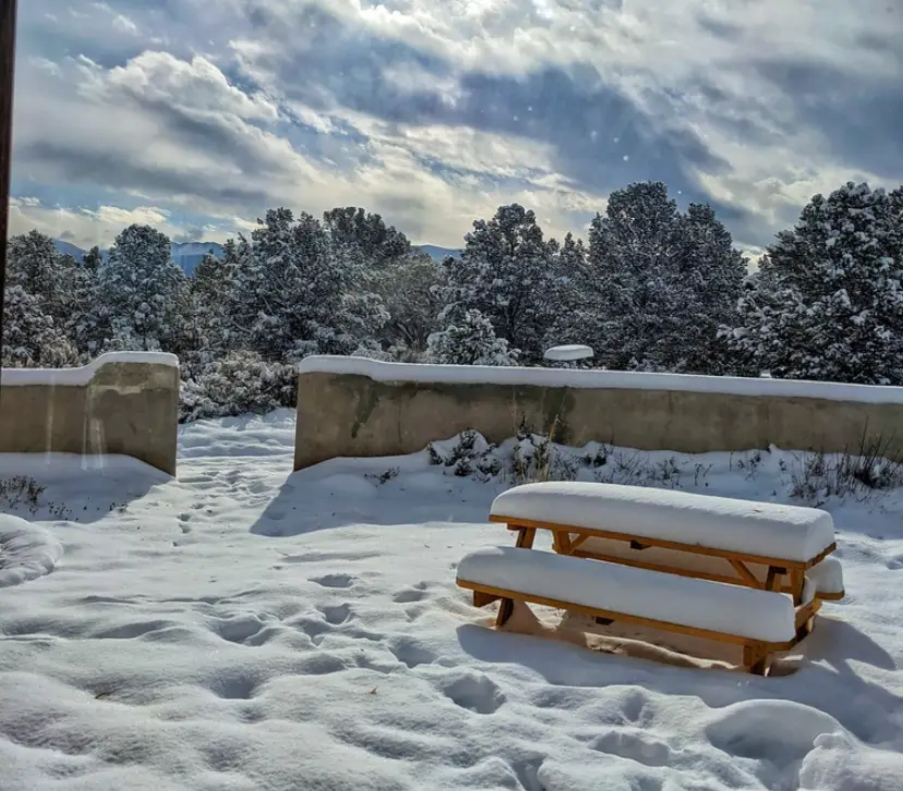 A picnic table covered in layers of snow at the writer's off-grid house.