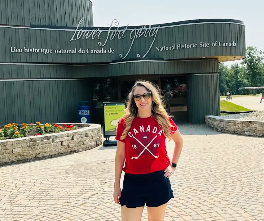 The writer wearing a red Canada shirt and standing in front of a historical site in Canada.