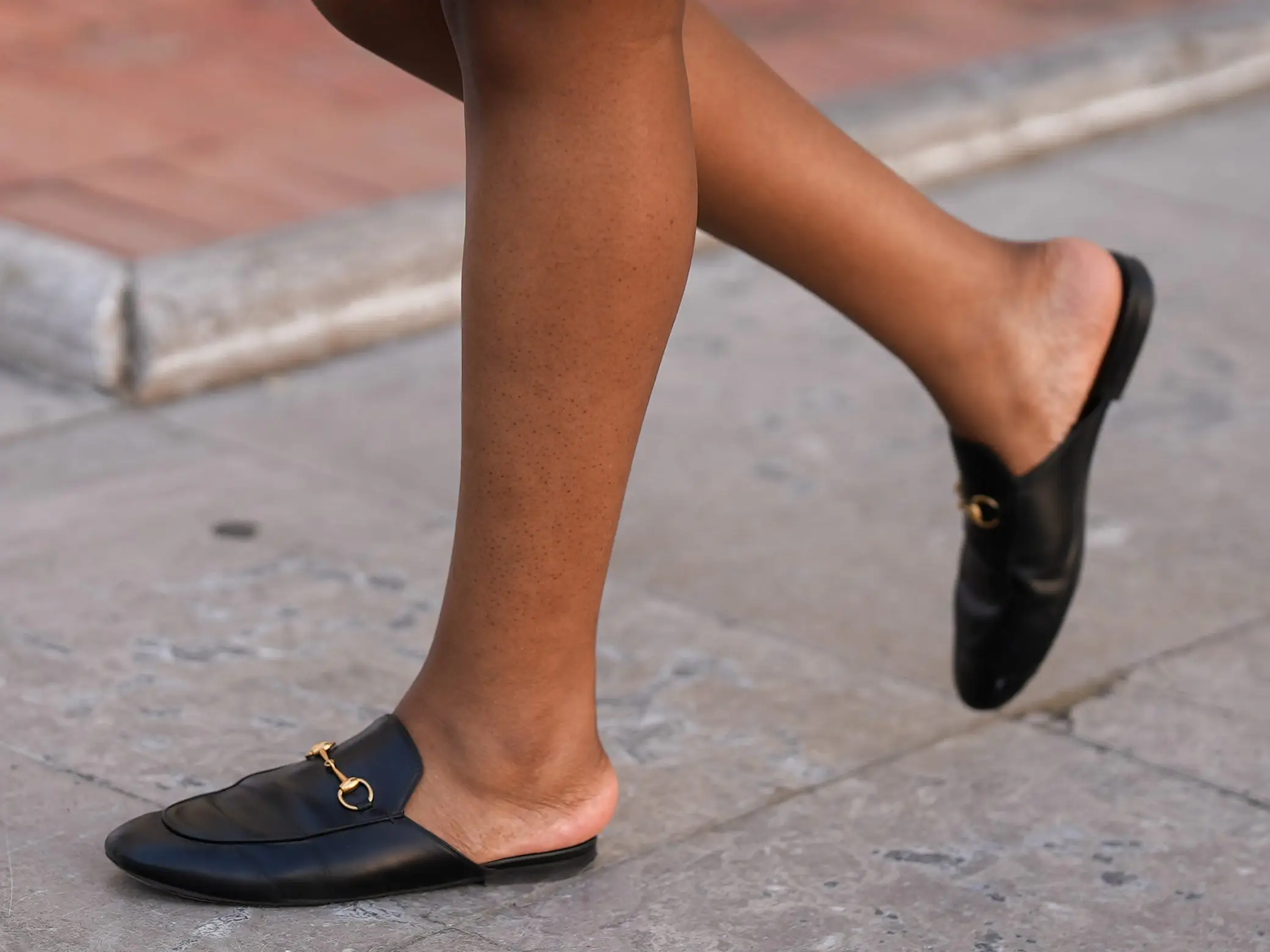 A woman wearing black mules with no backs.