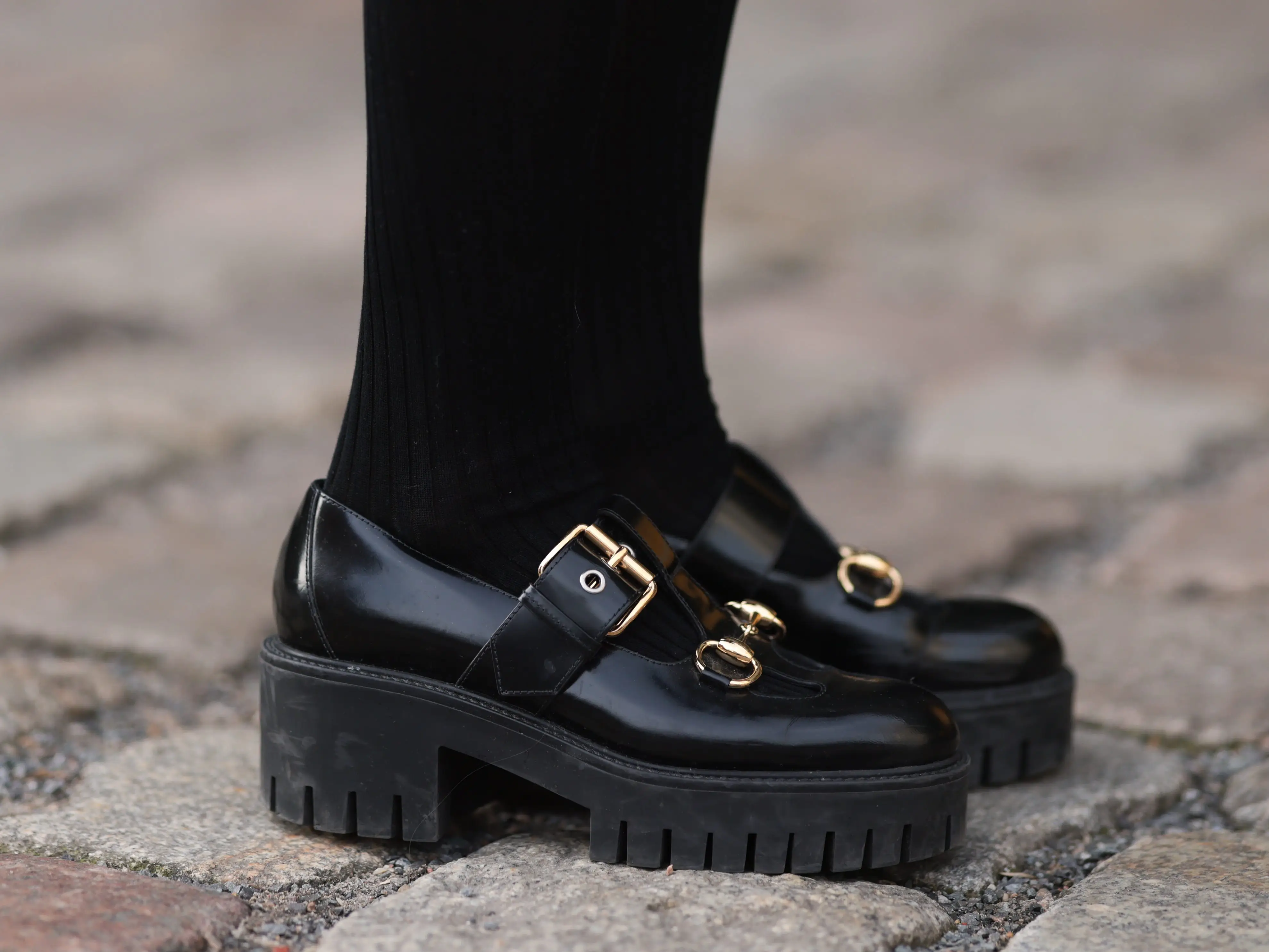 A person wearing black loafers with a chunky sole.