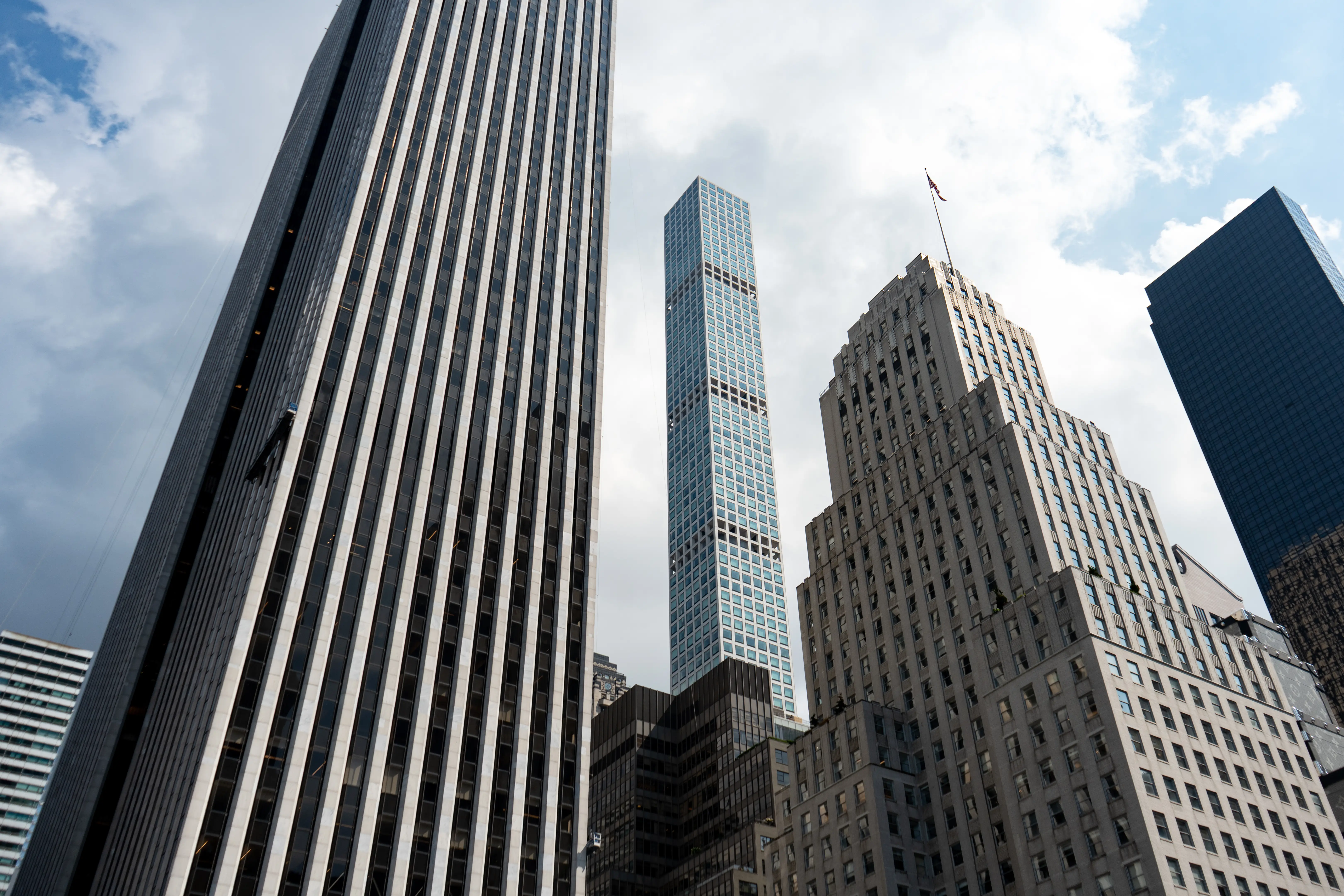 Low-angle view of tall skyscrapers against a partly cloudy sky in a dense urban business district.