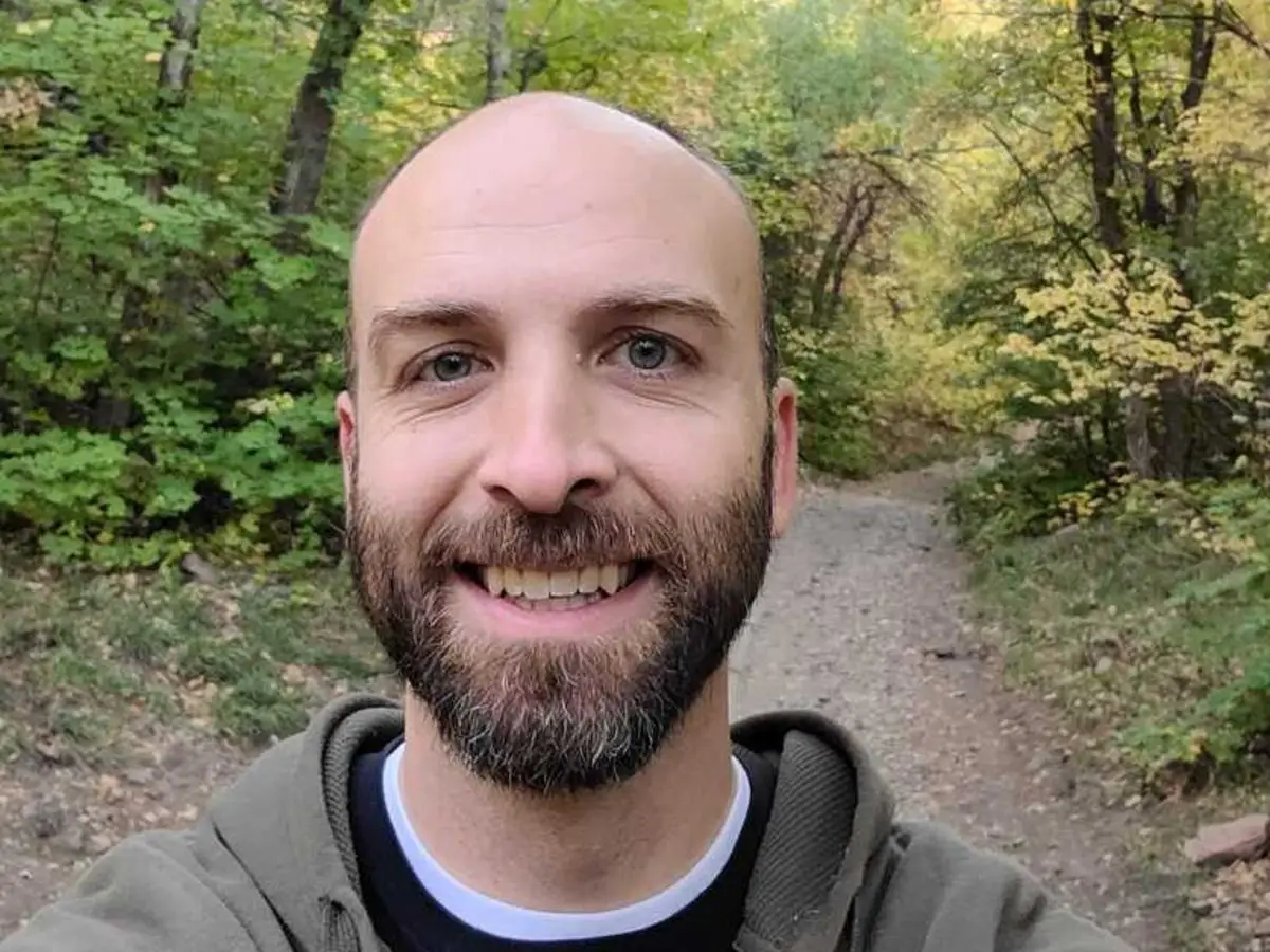 a bald man takes a selfie in the forest