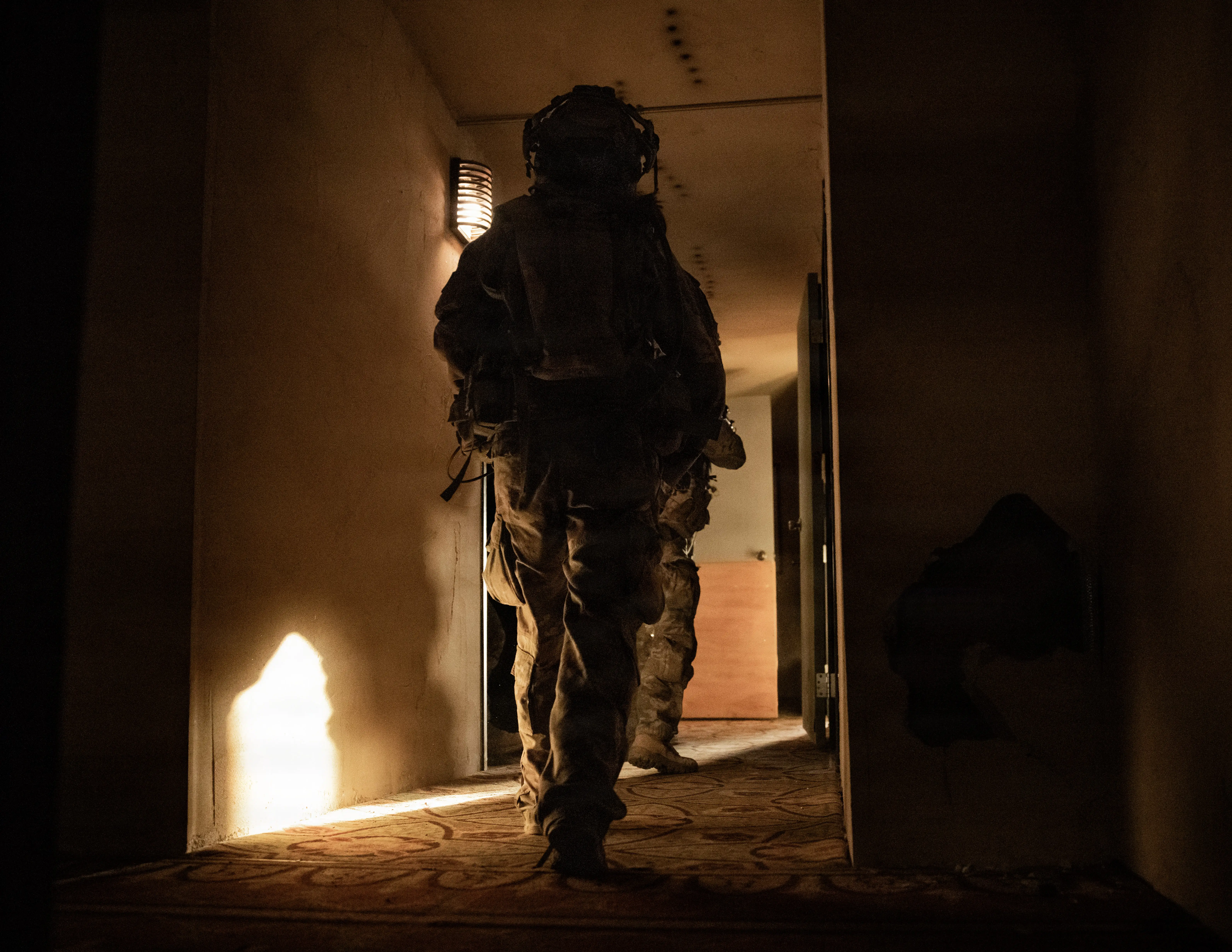 US Army soldiers run through dark hallways.