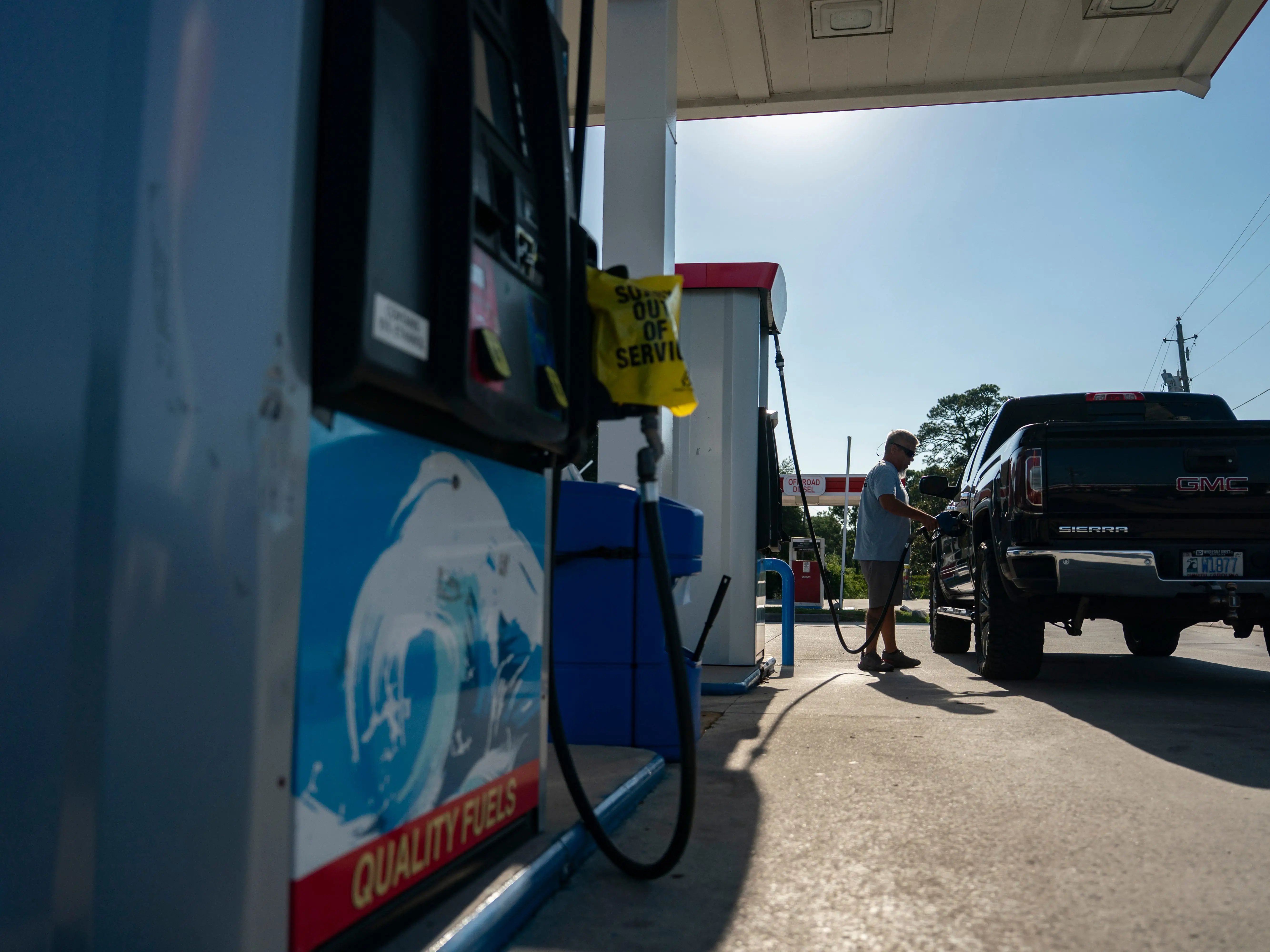 A man fills up his truck with gas at a gas station.