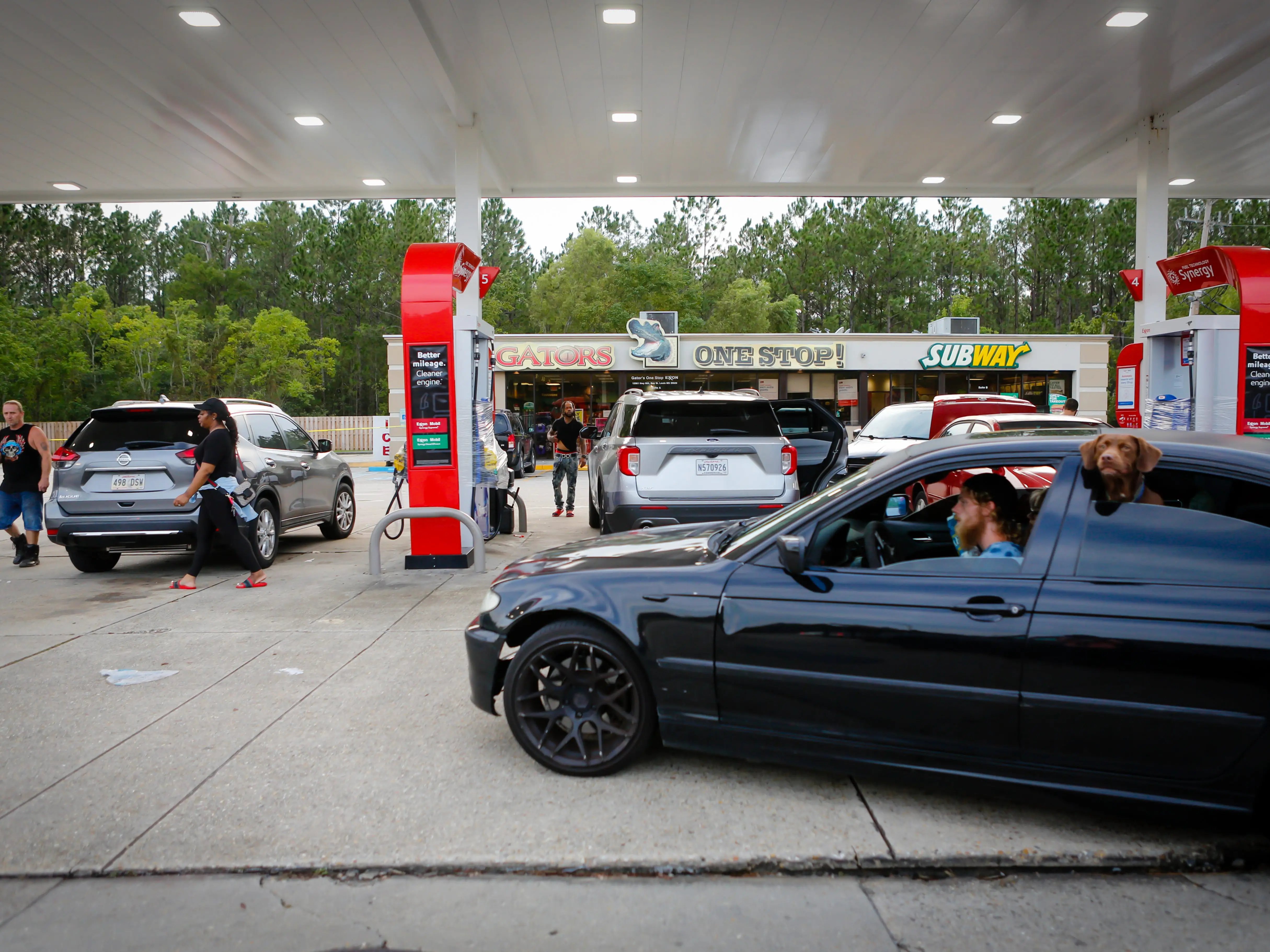 A driver in a black sedan pulls up to a gas station.