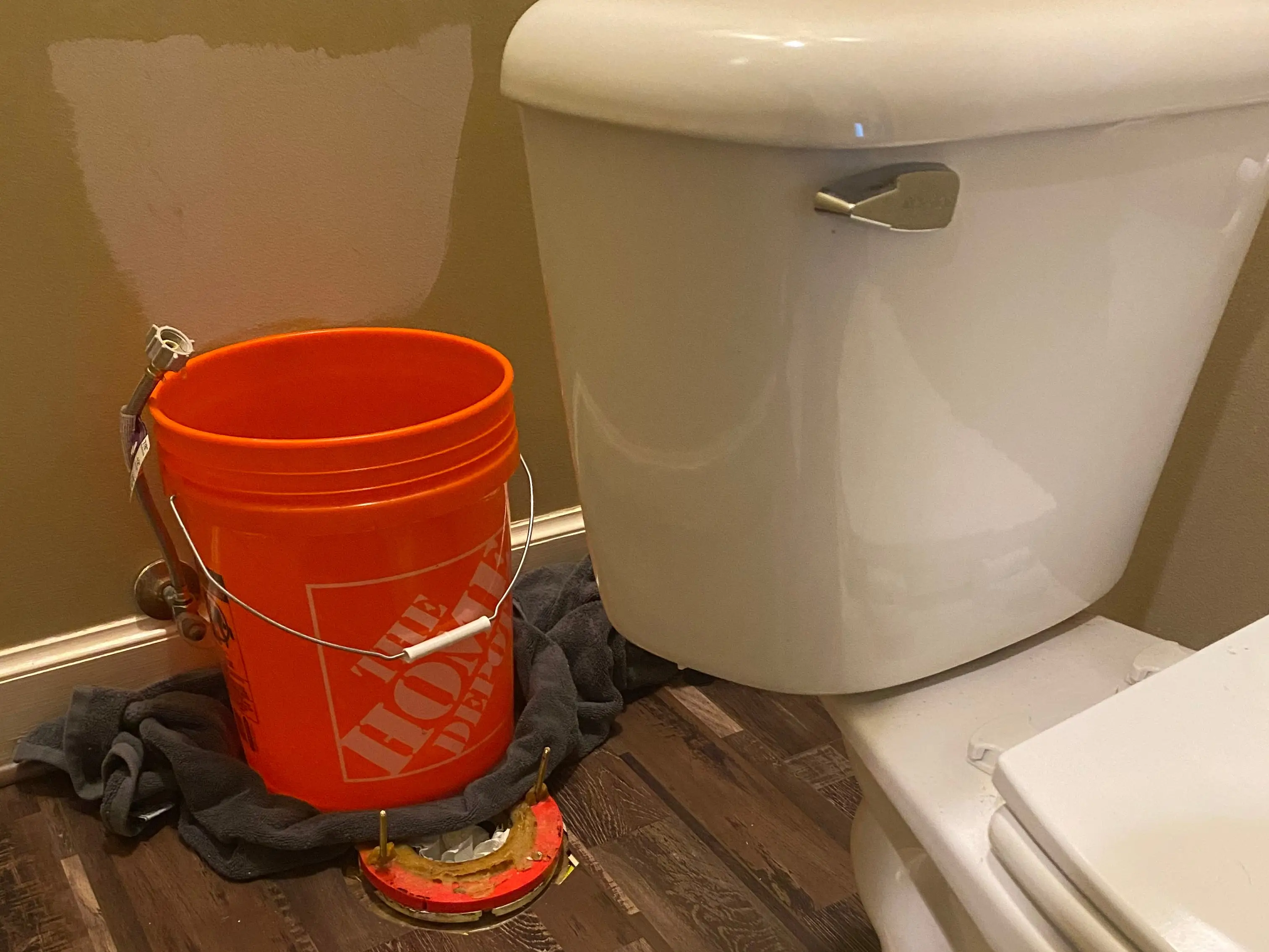 Home DEpot bucket behind toilet on top of vinyl flooring