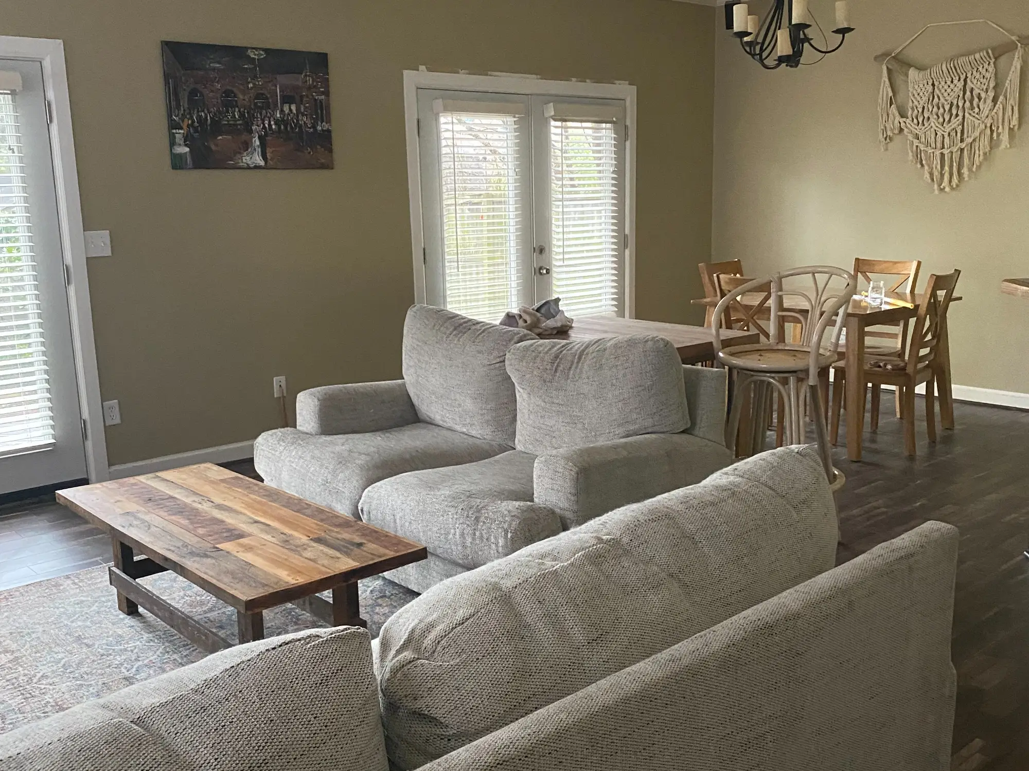 Living room with green walls, light gray couches, and vinyl-plank flooring next to French doors