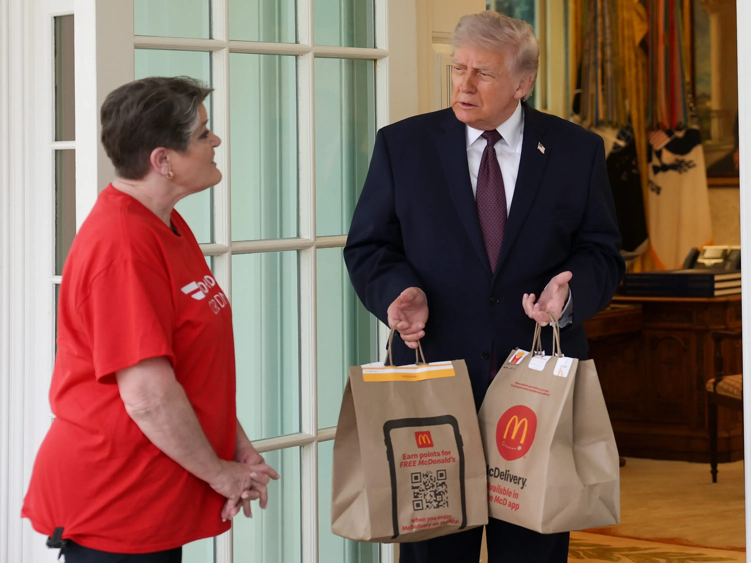 President Donald Trump receives a DoorDash delivery of McDonald's from Sharon Simmons before he speaks to the press during an event outside the Oval Office of the White House on April 13, 2026 in Washington, DC.