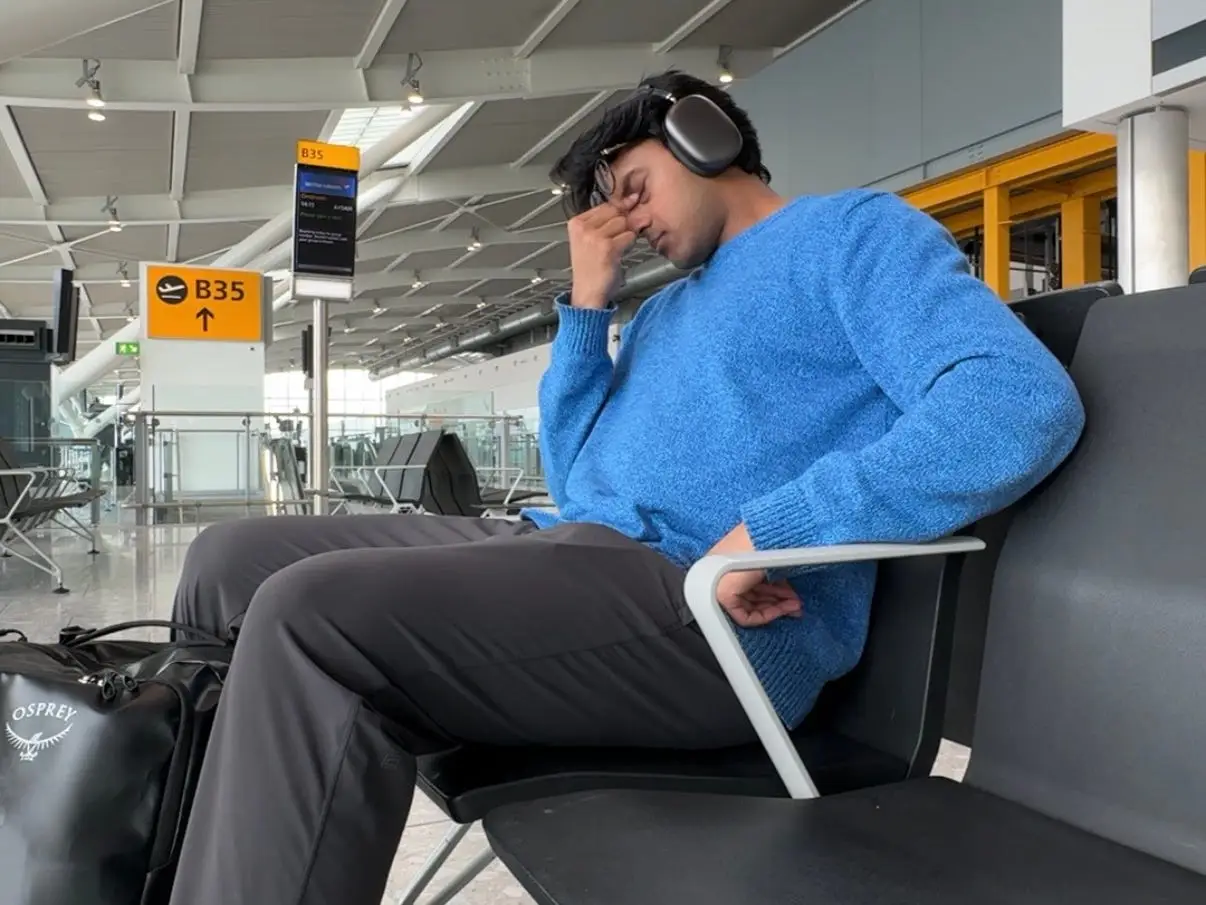 Man in blue sweater looking frustrated at an airport.
