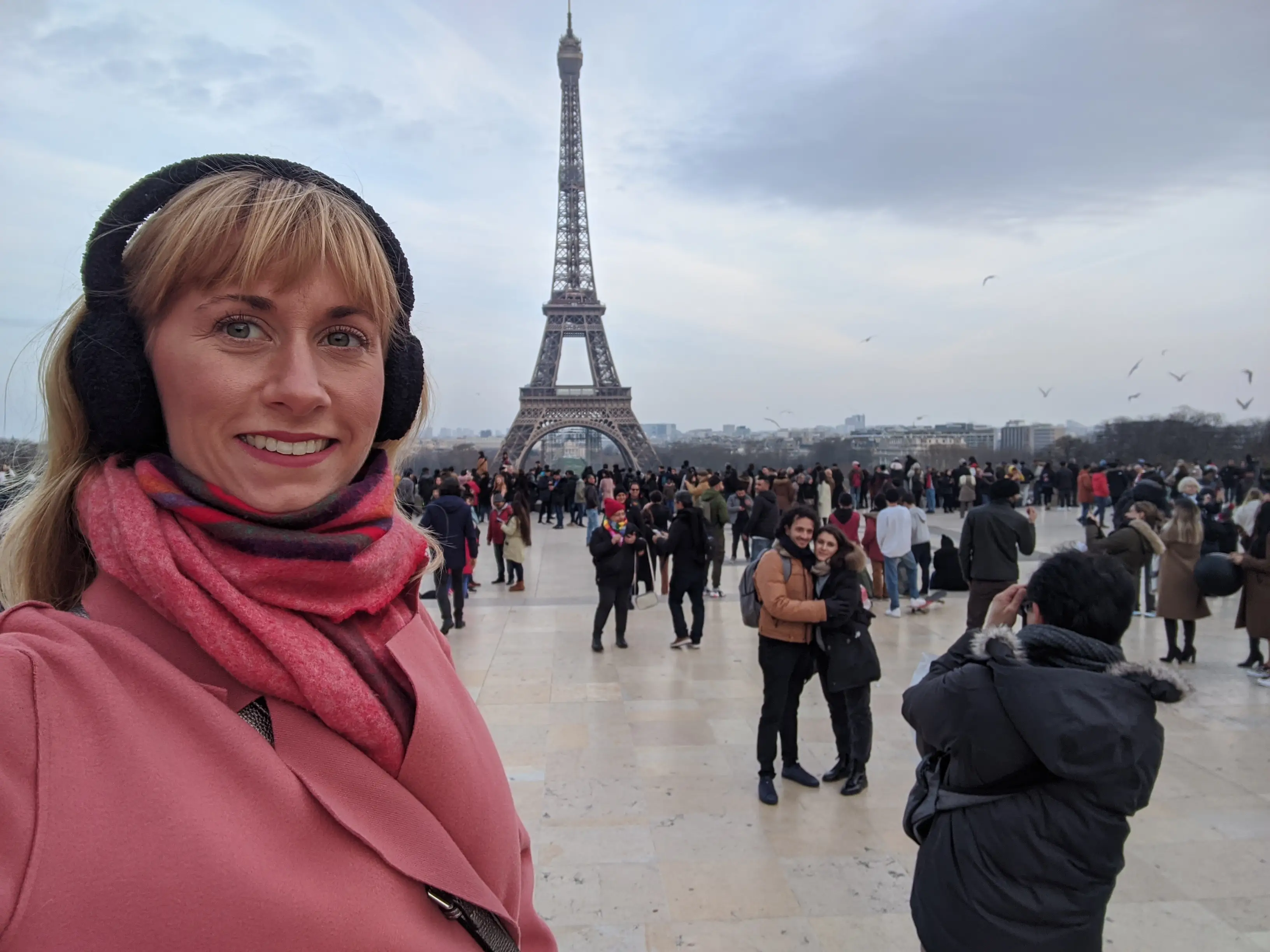 Leah Young poses for a selfie with the Eiffel Tower and with a crowd behind her.