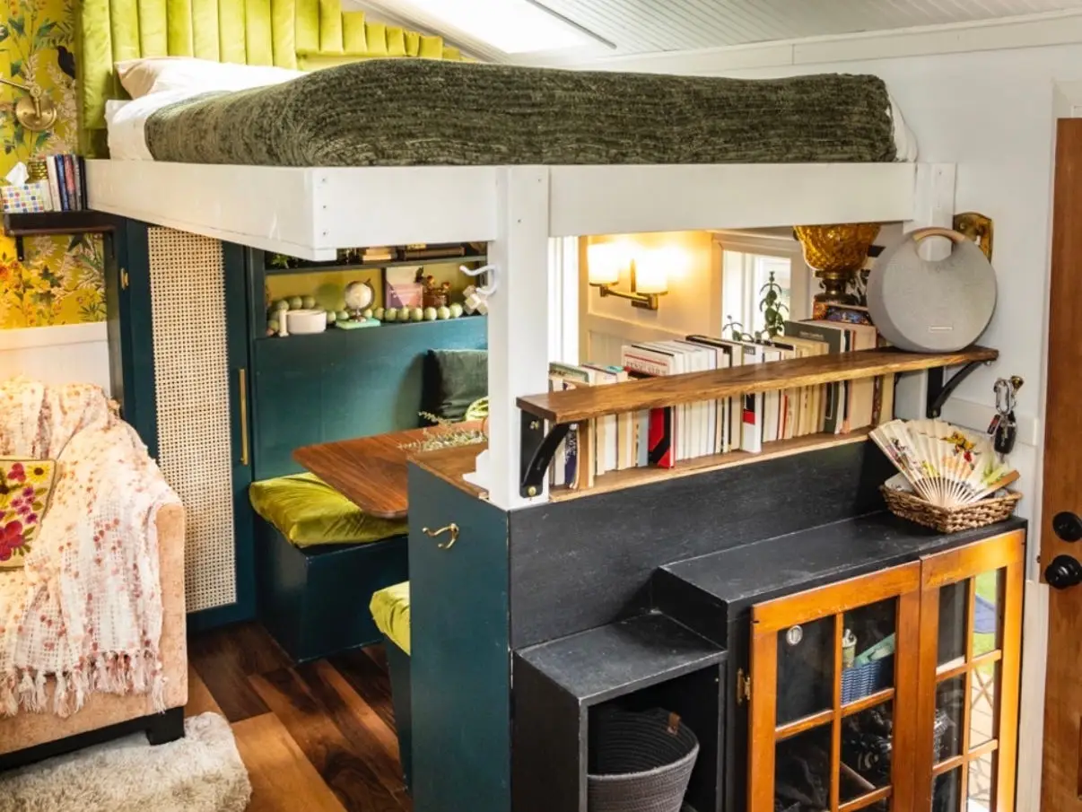 Margo Fairchild's tiny home with a loft bed, built-in shelves, wood floors, and a decorative hanging lantern.