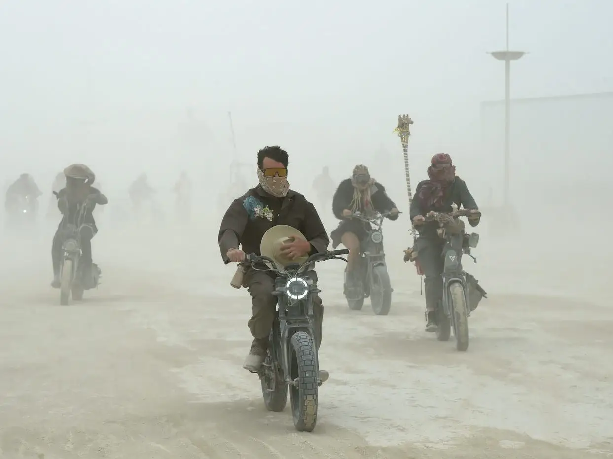 Motorcyclists ride through a dusty whiteout.