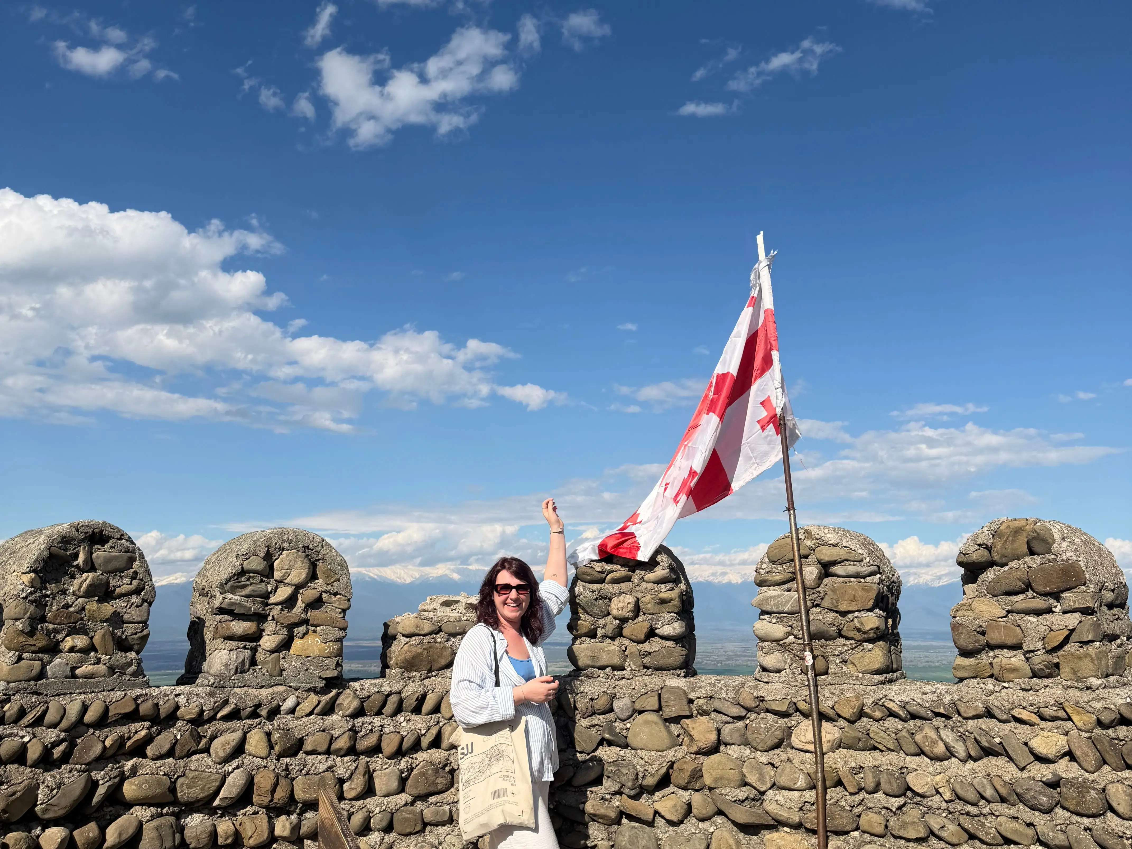 A woman standing in Georgia near the nation's flag.