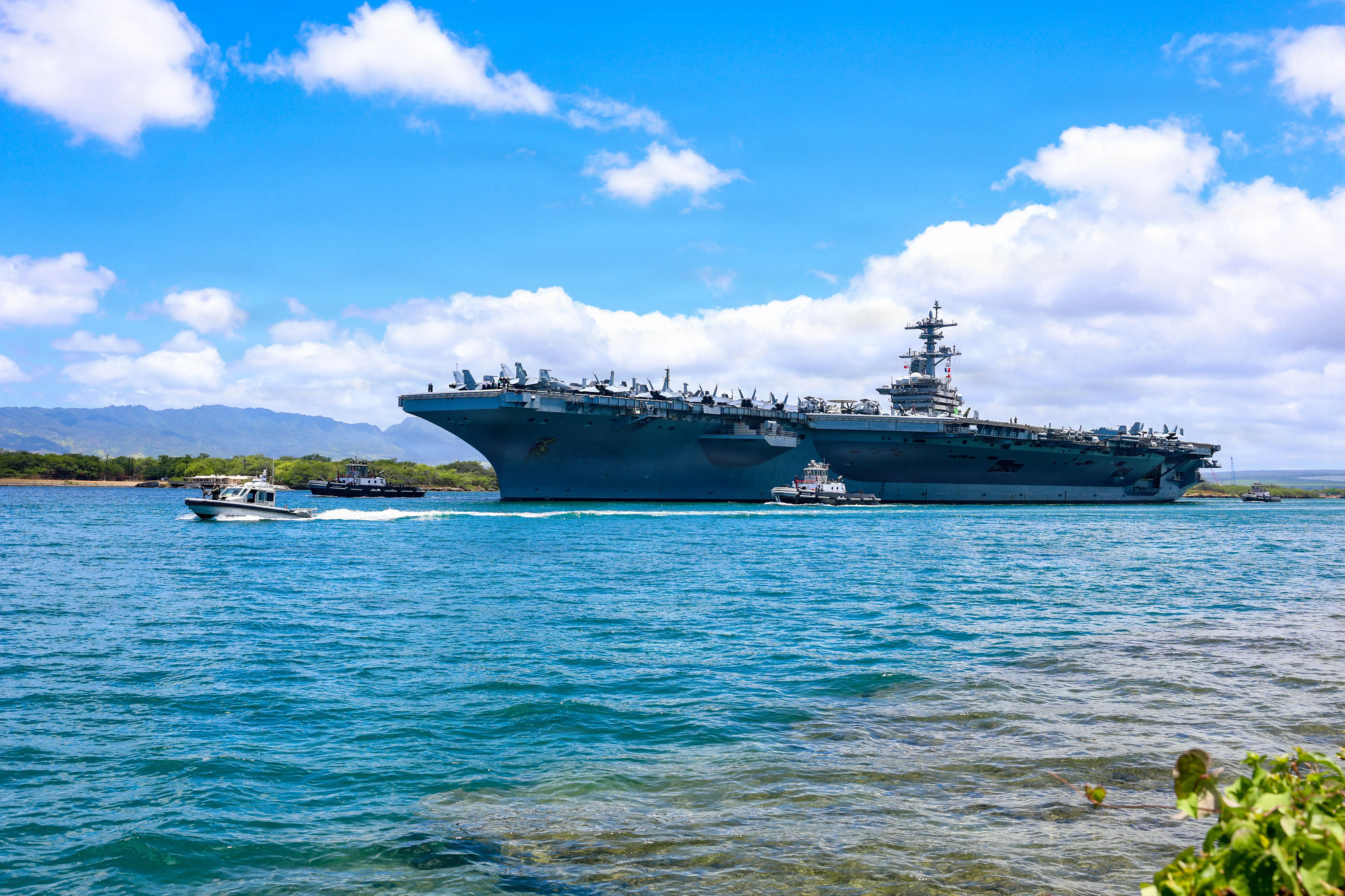 The US Navy USS Theodore Roosevelt aircraft carrier is seen in tropical blue waters.