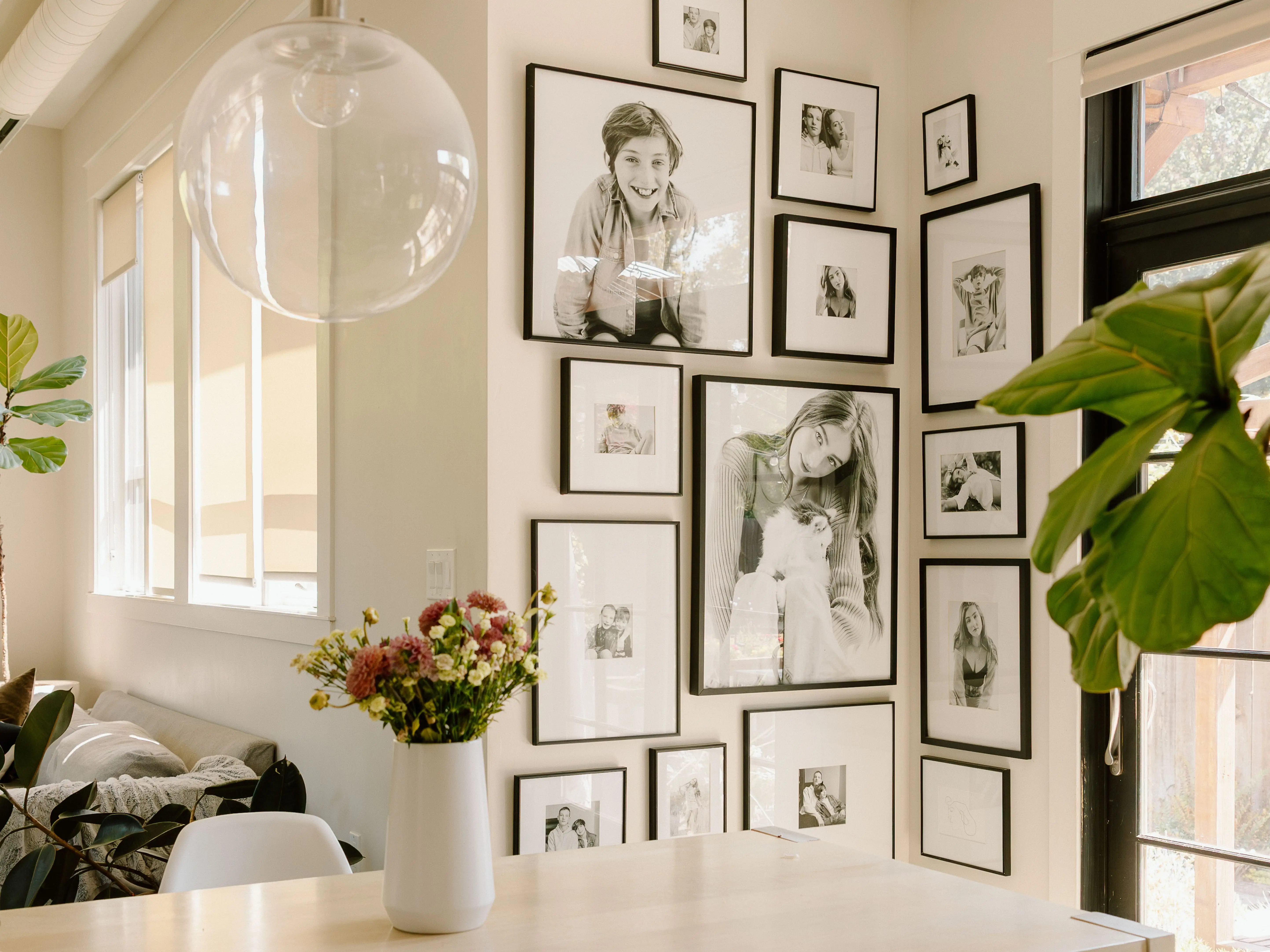 Gallery wall of black and white portrats behind light wood table