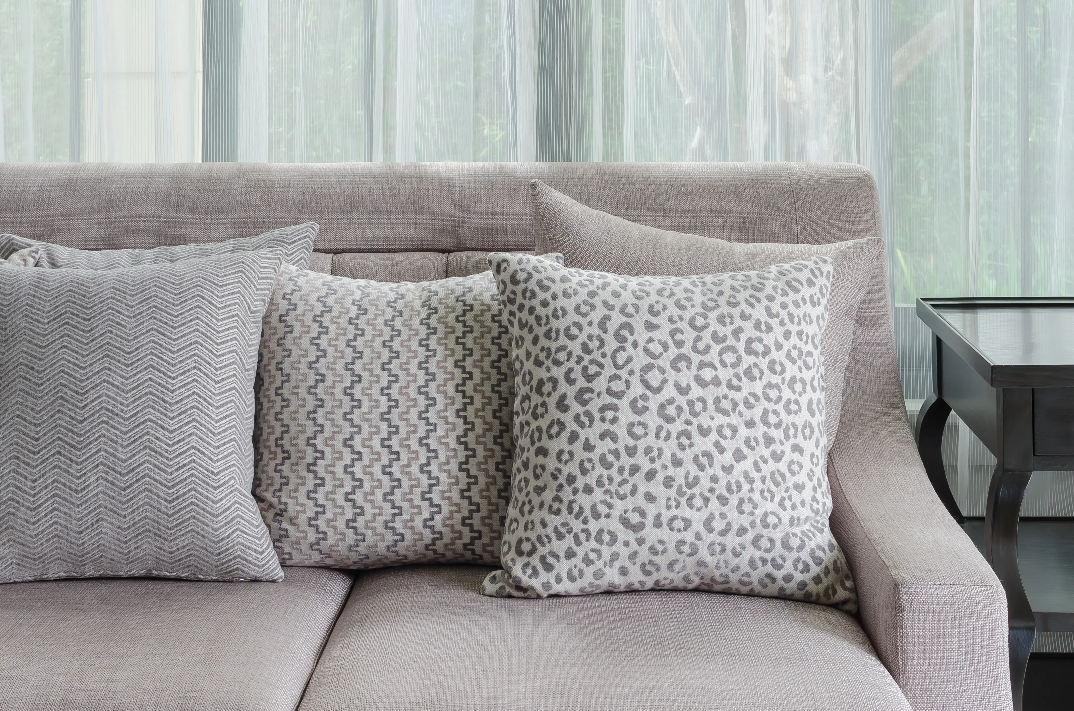 Neutral colored pillows on couch, one cheetah print, one chevron