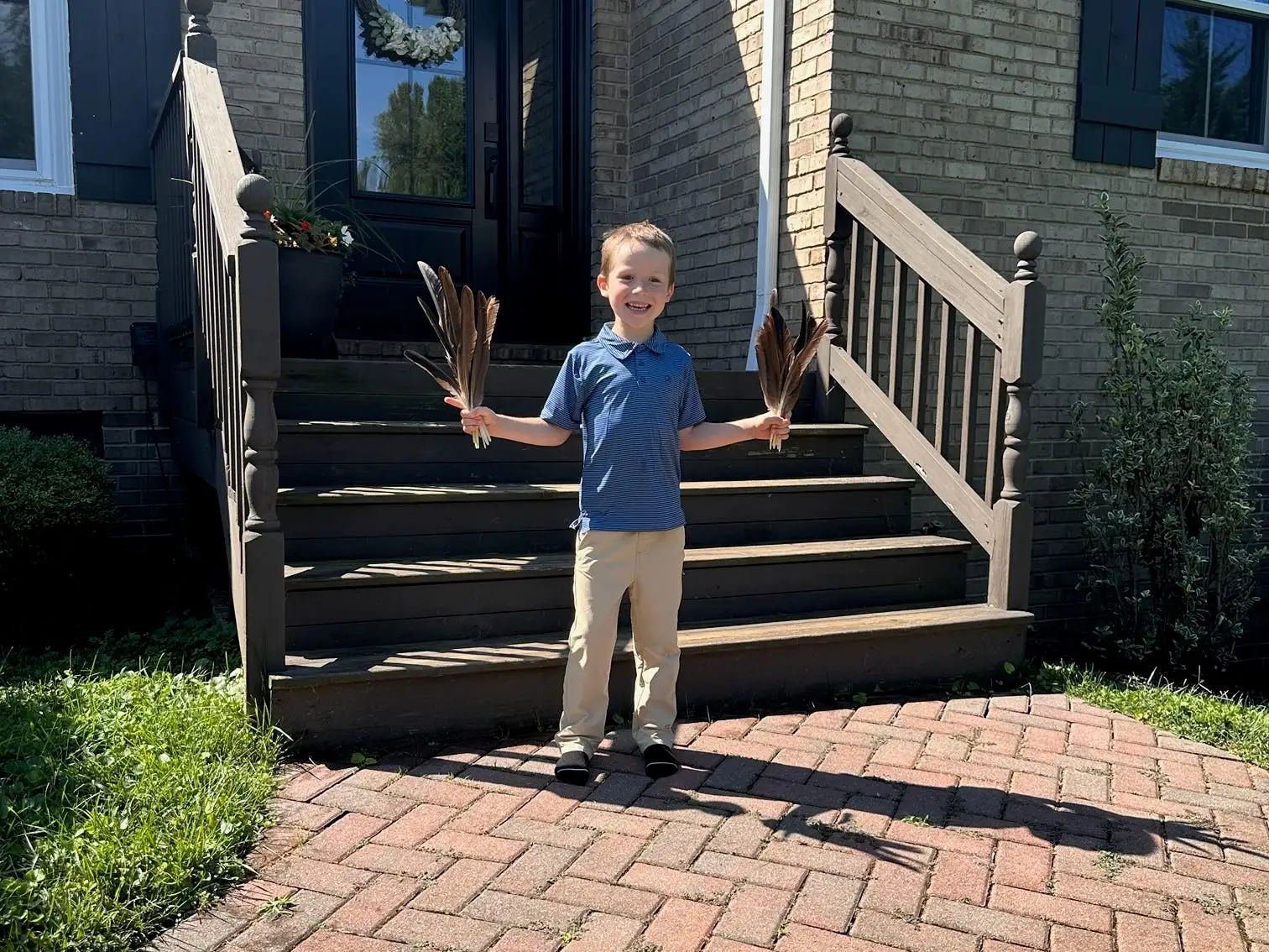 A young boy holding goose feathers.