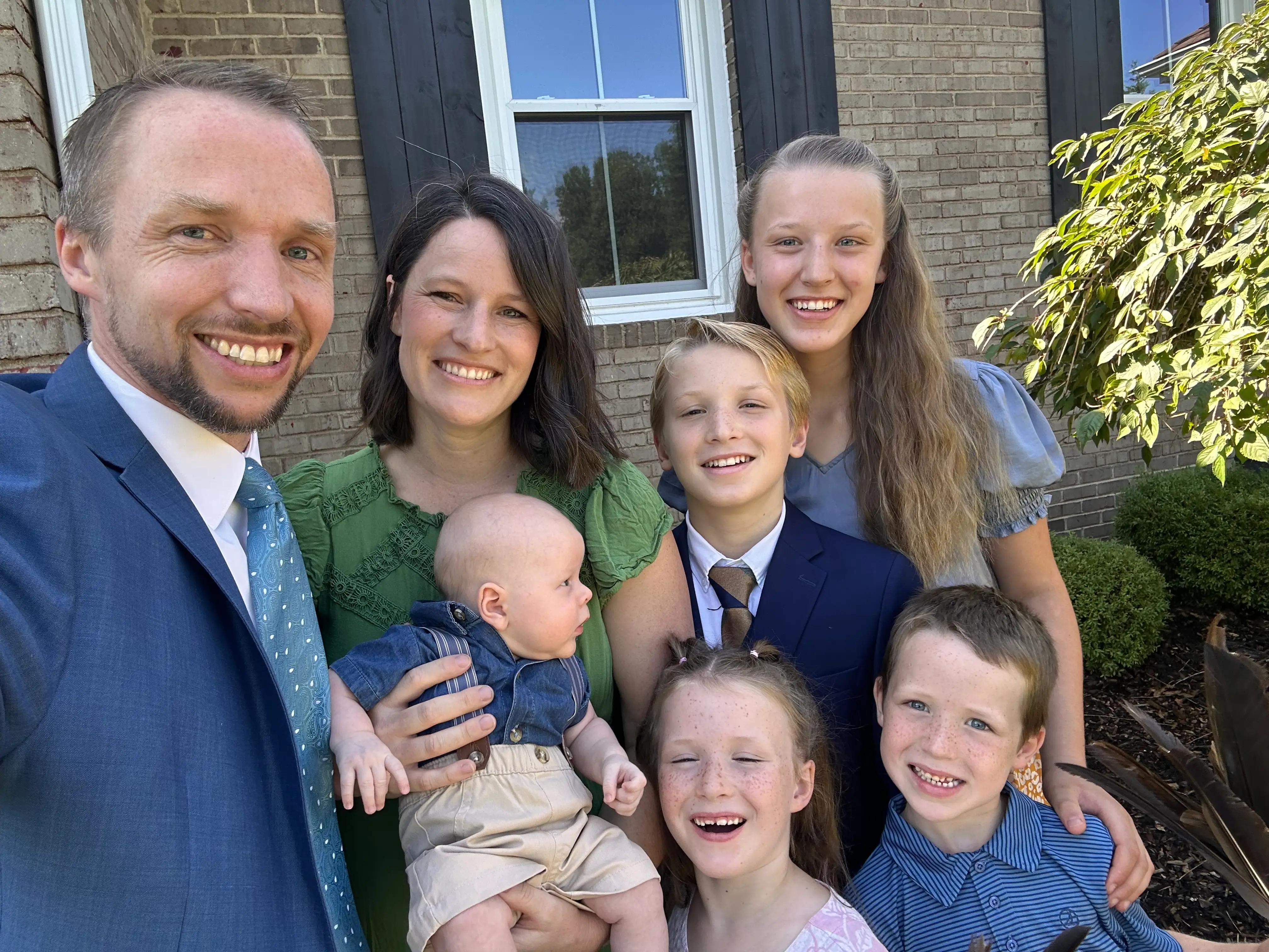 A family of two parents and five children taking a selfie.