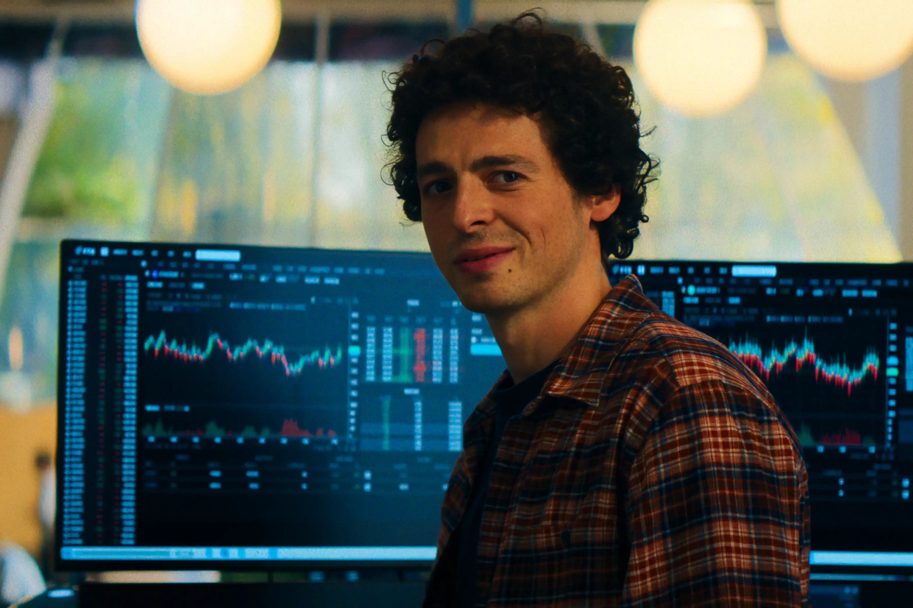 Anthony Boyle as Sam Bankman-Fried sitting with screens in back of him