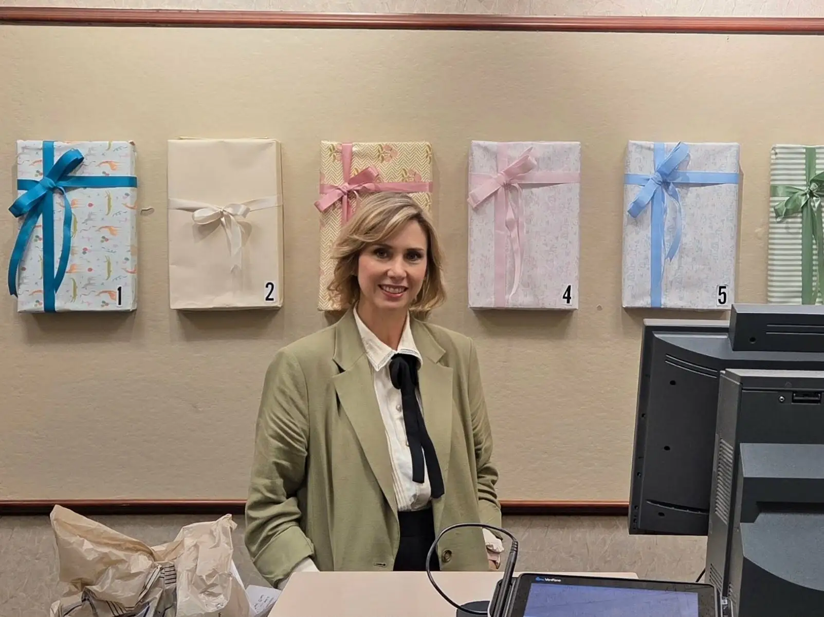 Woman smiling behind counter with gift wrapped boxes behind her