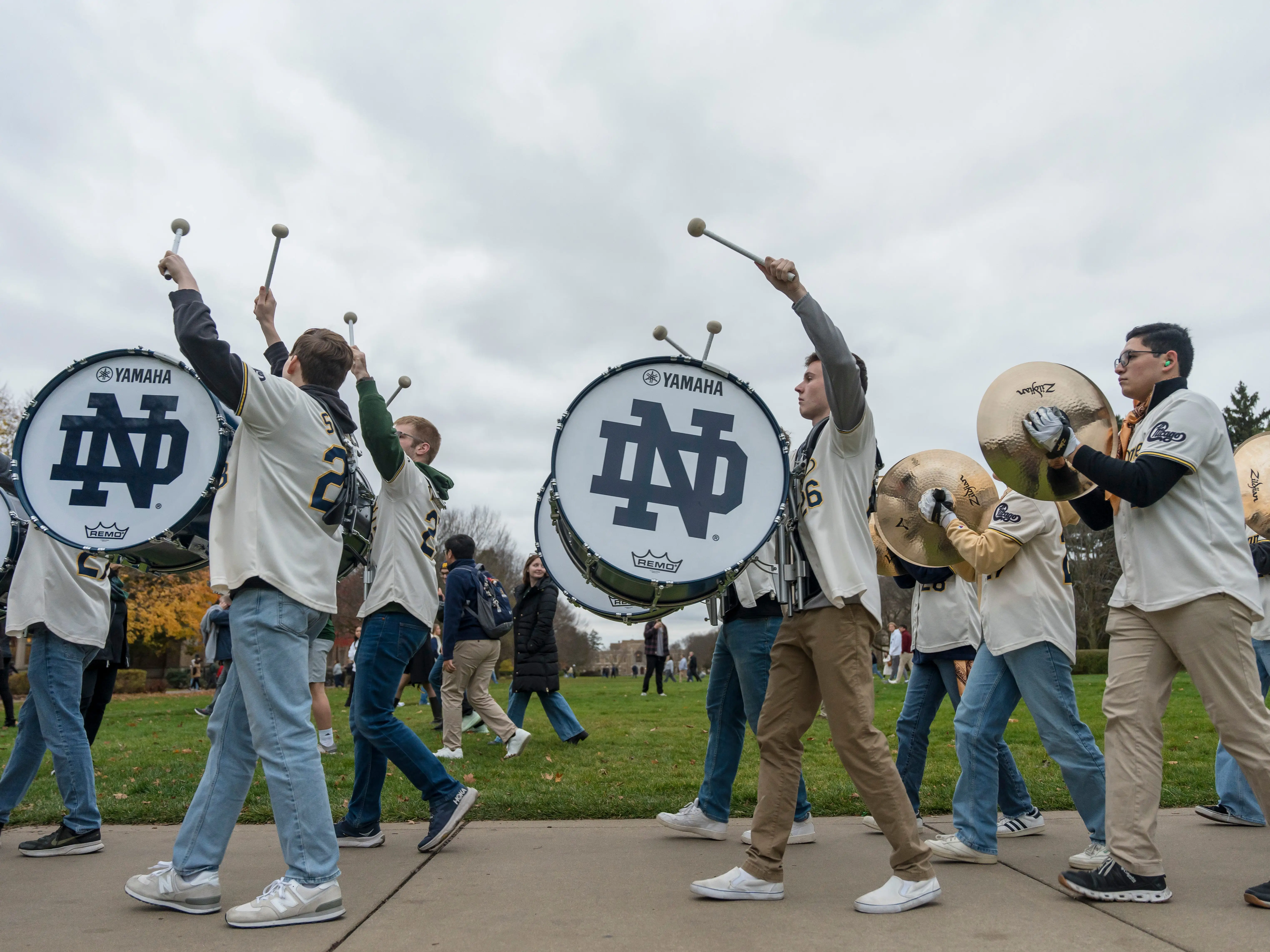 A marching band walks across a college campus.