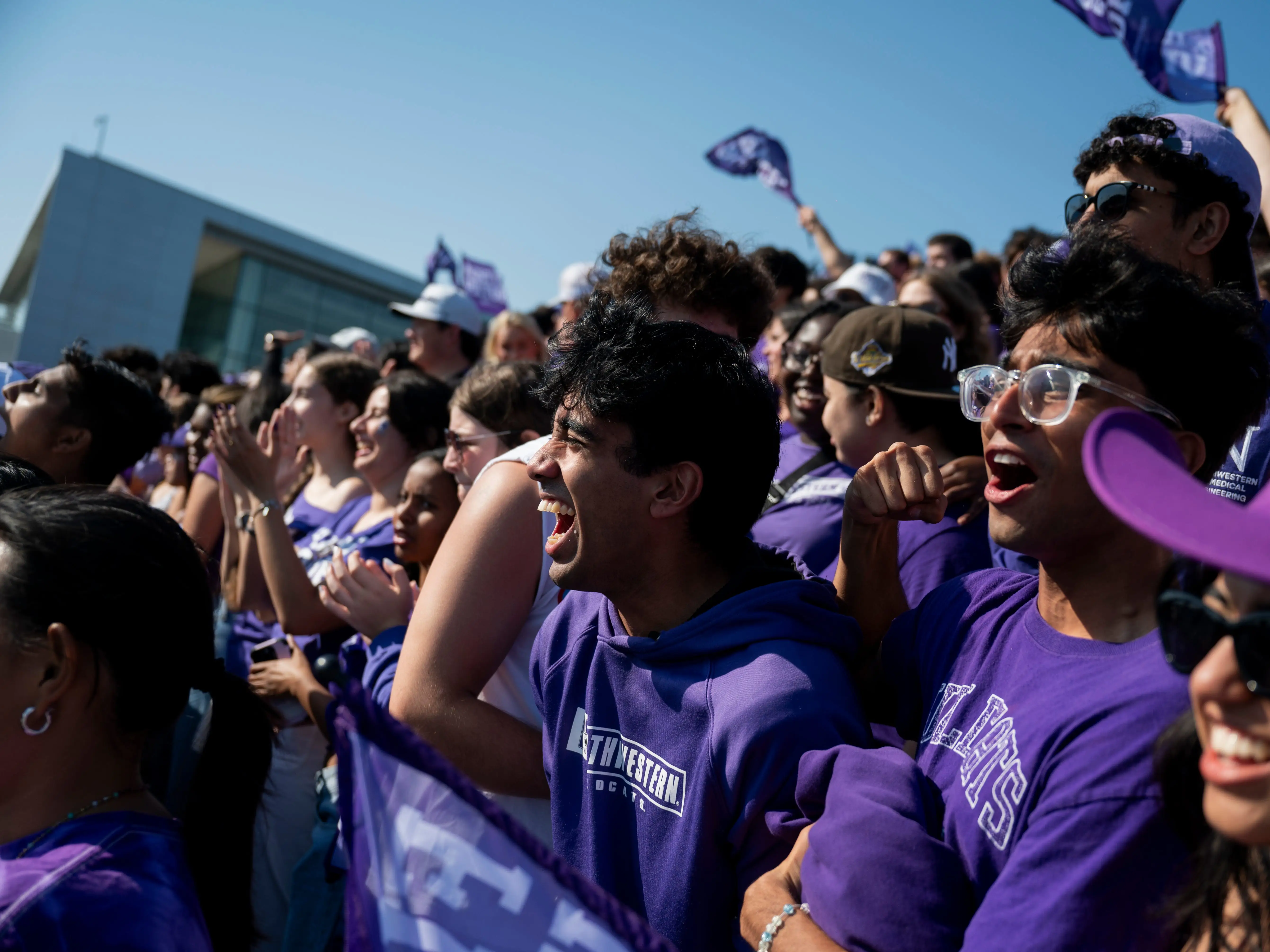 Students in purple attire cheer on a football game.