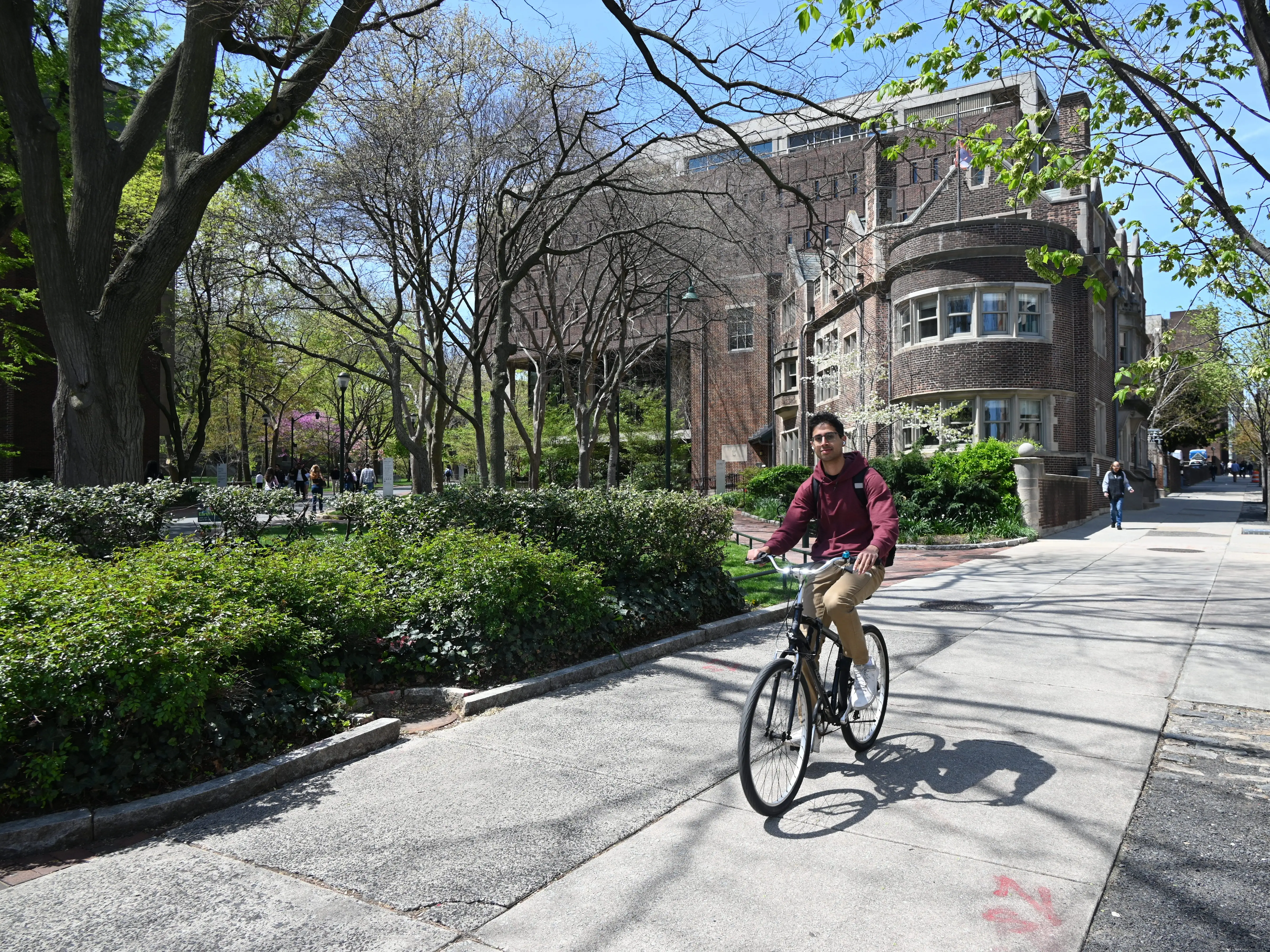 A student on a bike rides through a college campus.