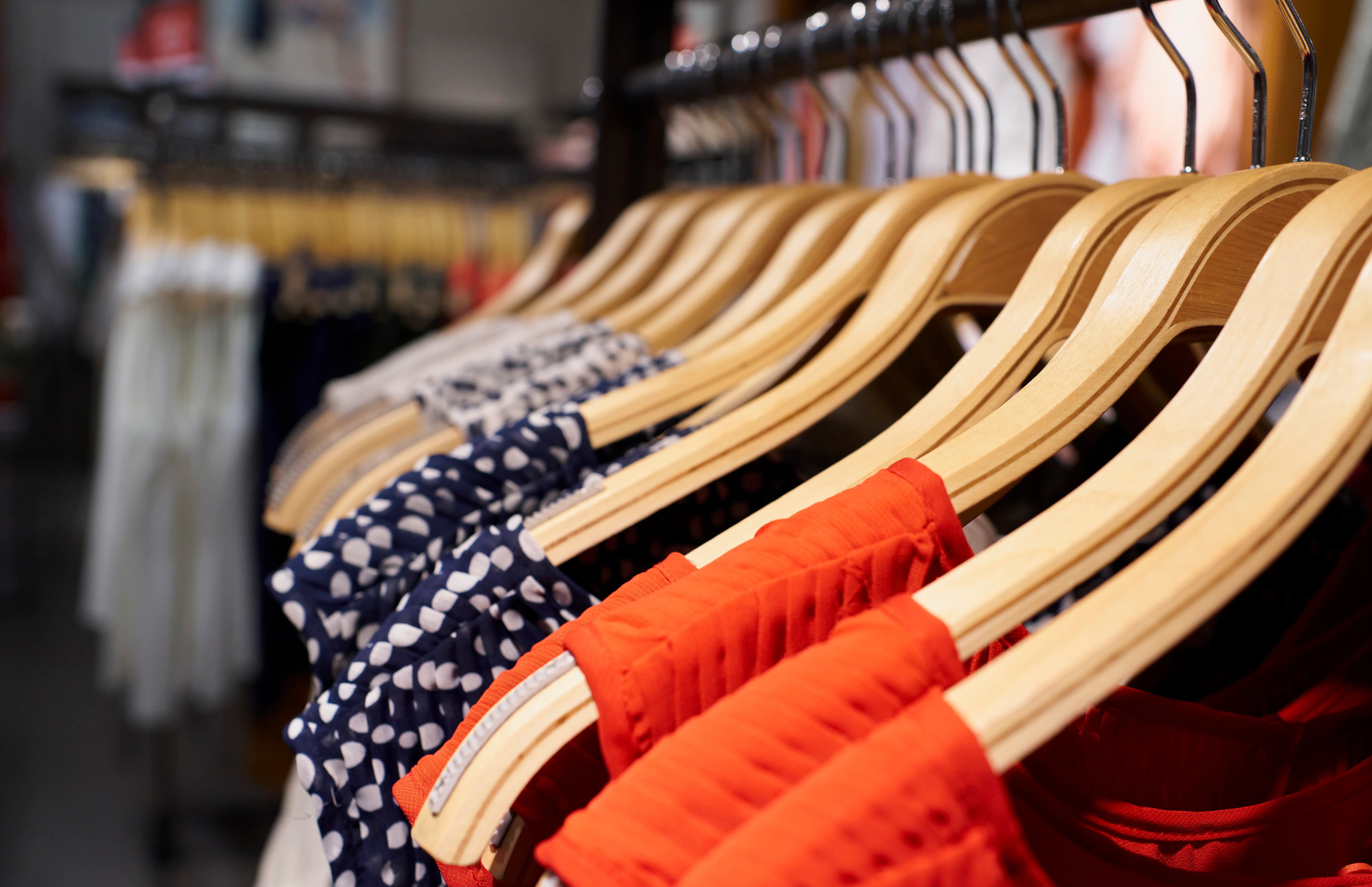 Close-up view of women's dresses hanging on clothes hooks in mall store rack