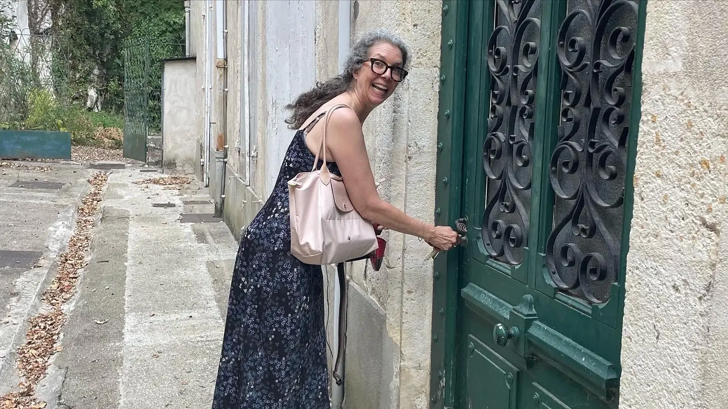 Woman smiling, opening large green doors