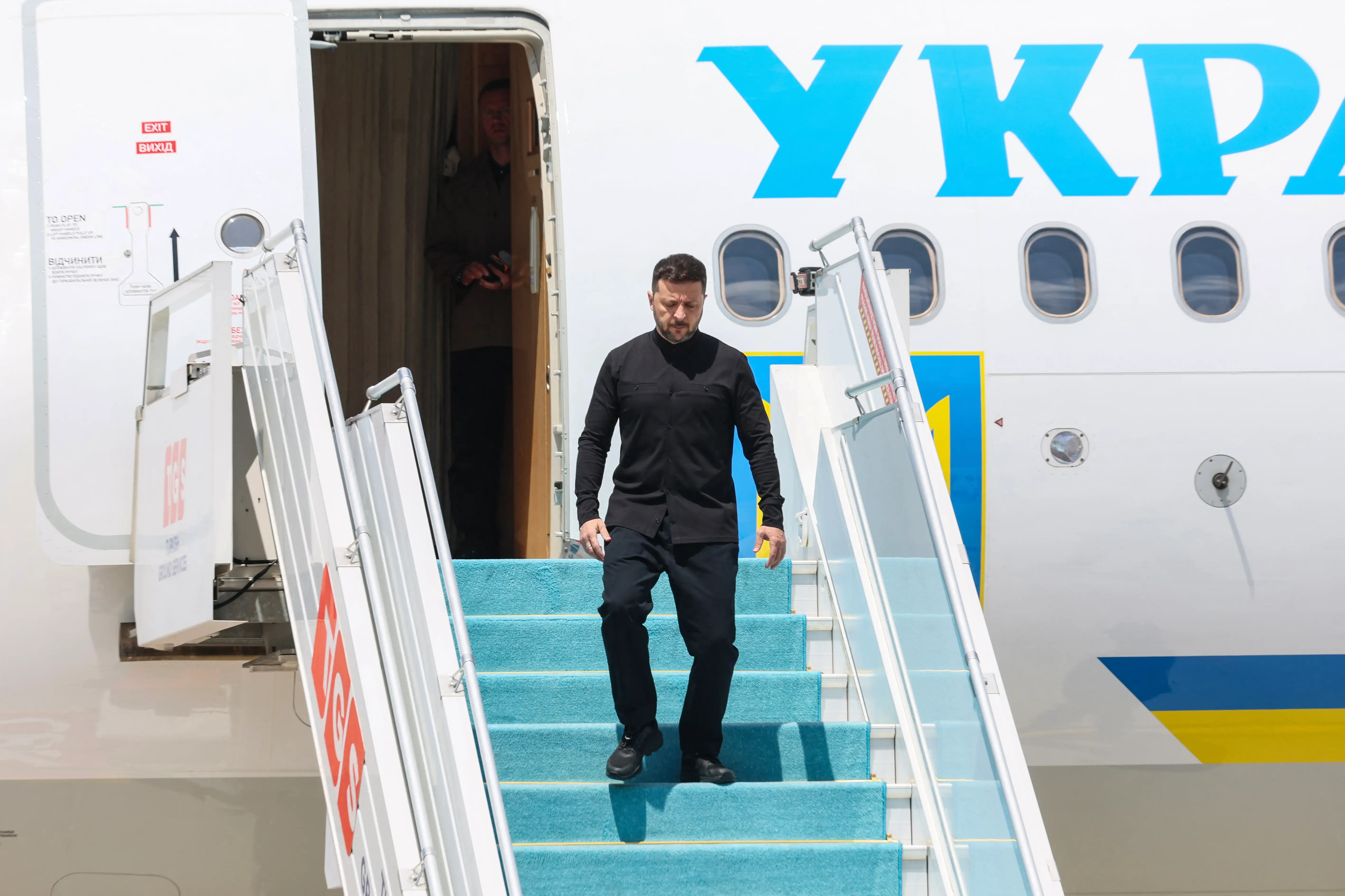 Zelenskyy walks down some passenger boarding stairs.
