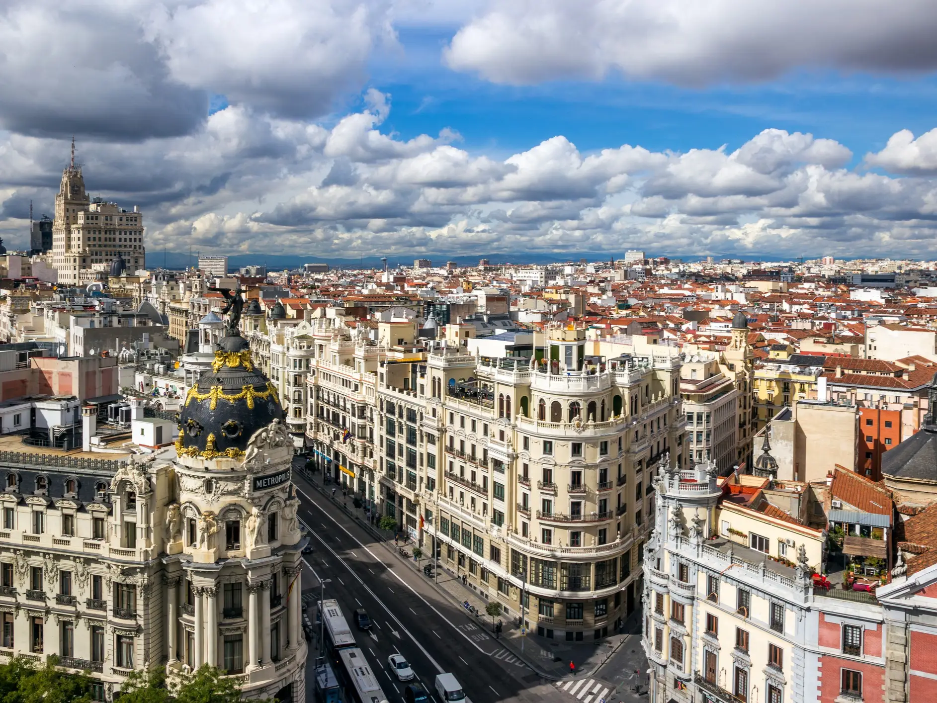 Gran Vía cityscape in Madrid with the Metrópolis Building, Edificio Telefónica, traffic, and dramatic clouds.