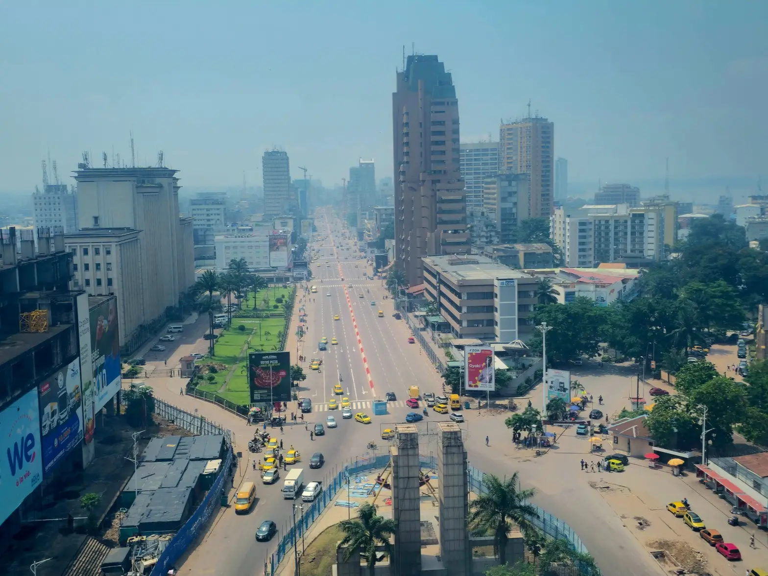 Elevated view of a broad urban boulevard with traffic, high-rises, billboards, and a hazy skyline.