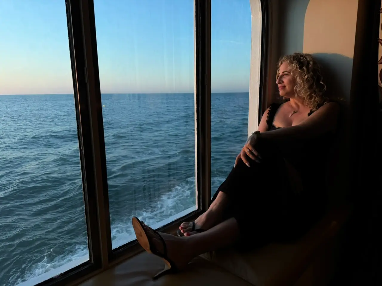 The author staring out the window on a cruise ship at the water.