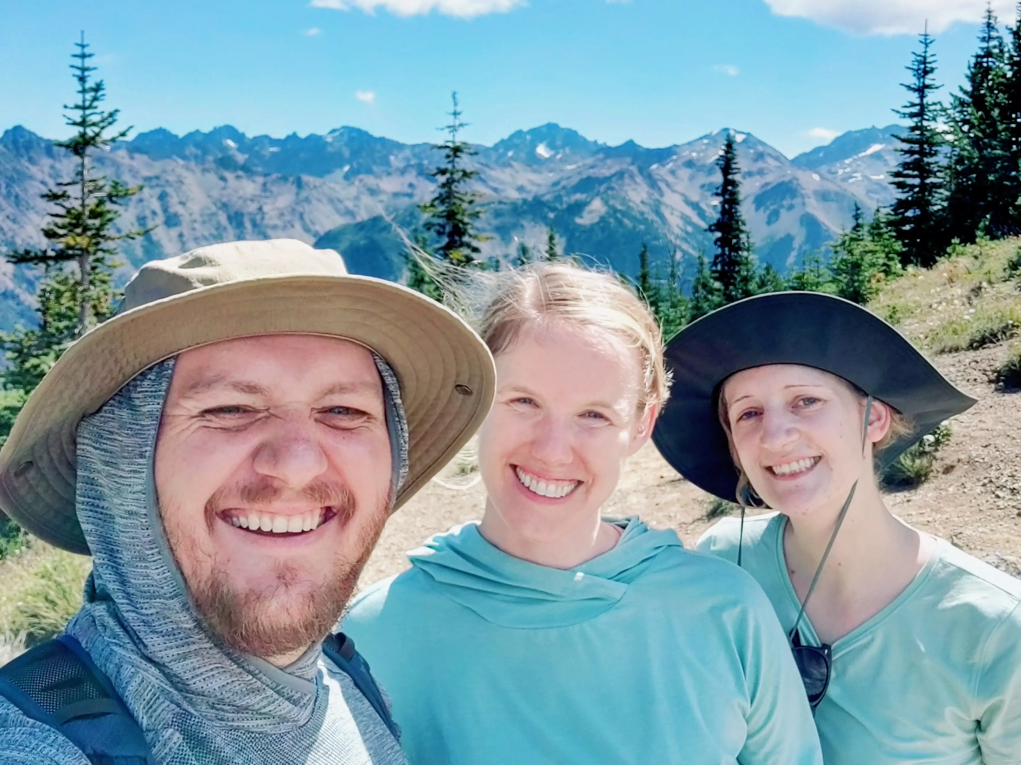 Laura Grace, her husband, and their friend pose for a photo on a hike.