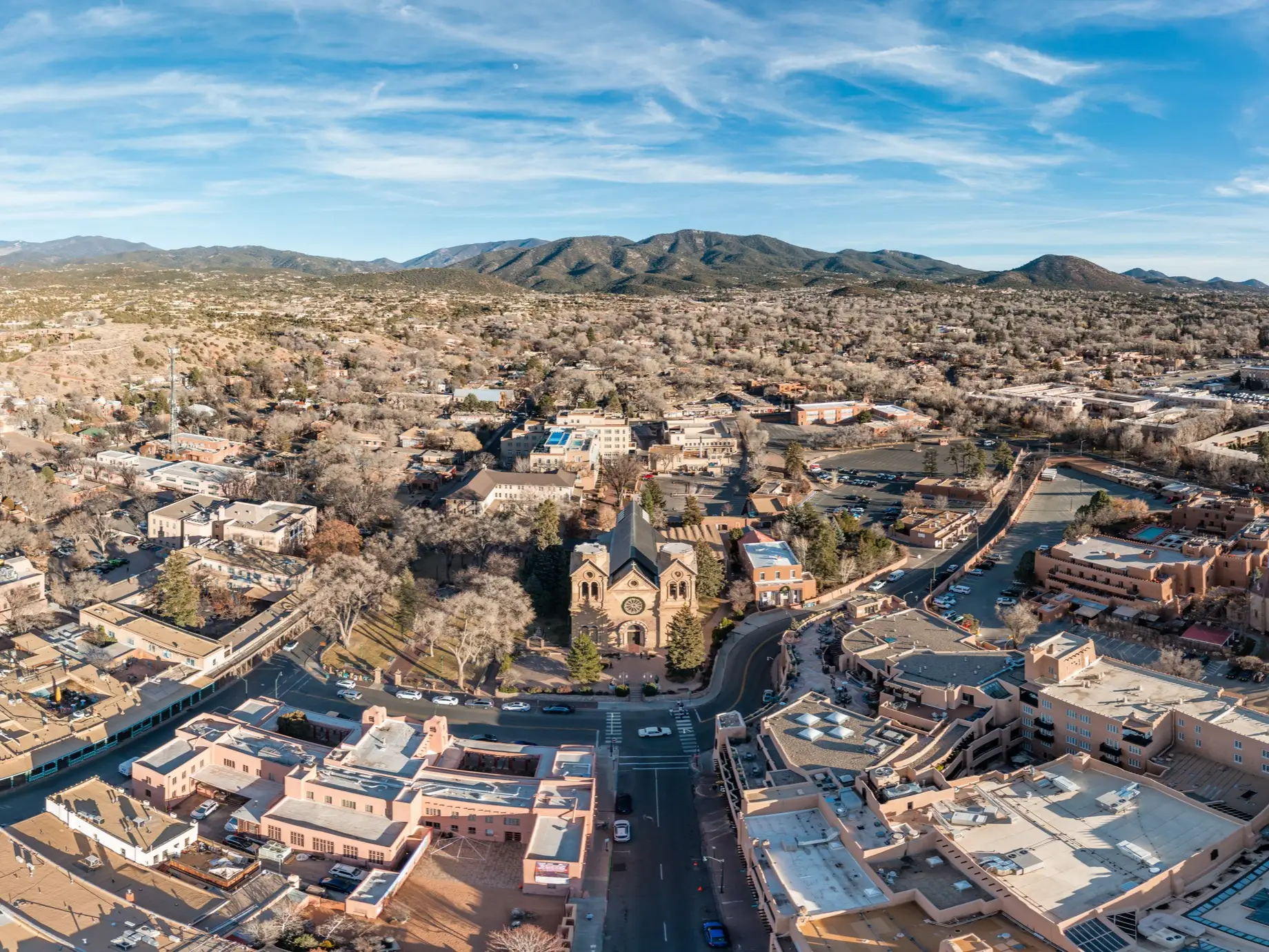 Aerial view of downtown Santa Fe with the Cathedral Basilica of St. Francis of Assisi and surrounding mountains.