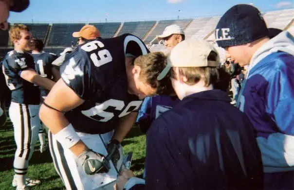 The author's husband signing an autograph for a fan while he played college football.