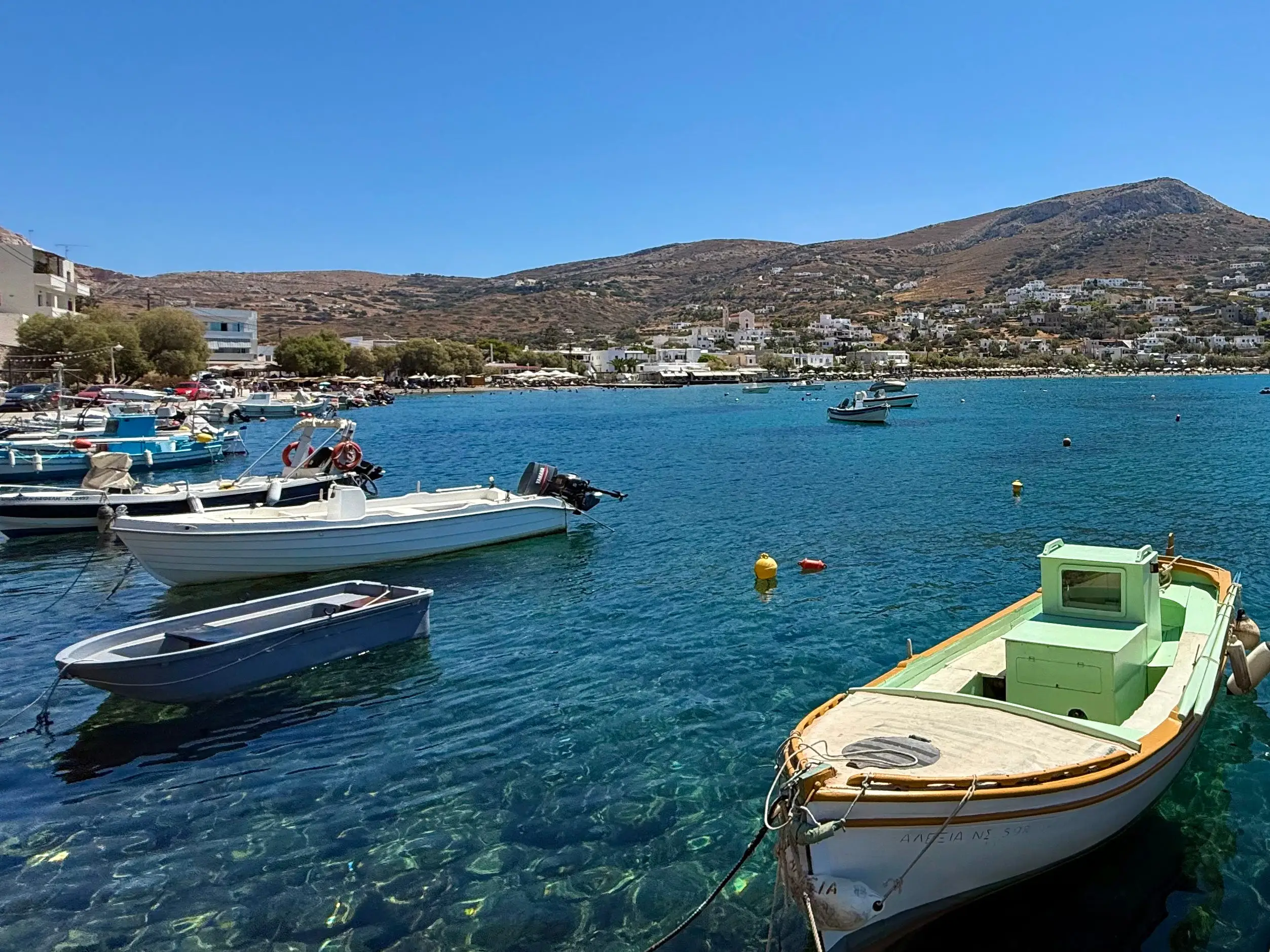 A number of boats are docked in crystal-clear water in the Greek island of Syros.