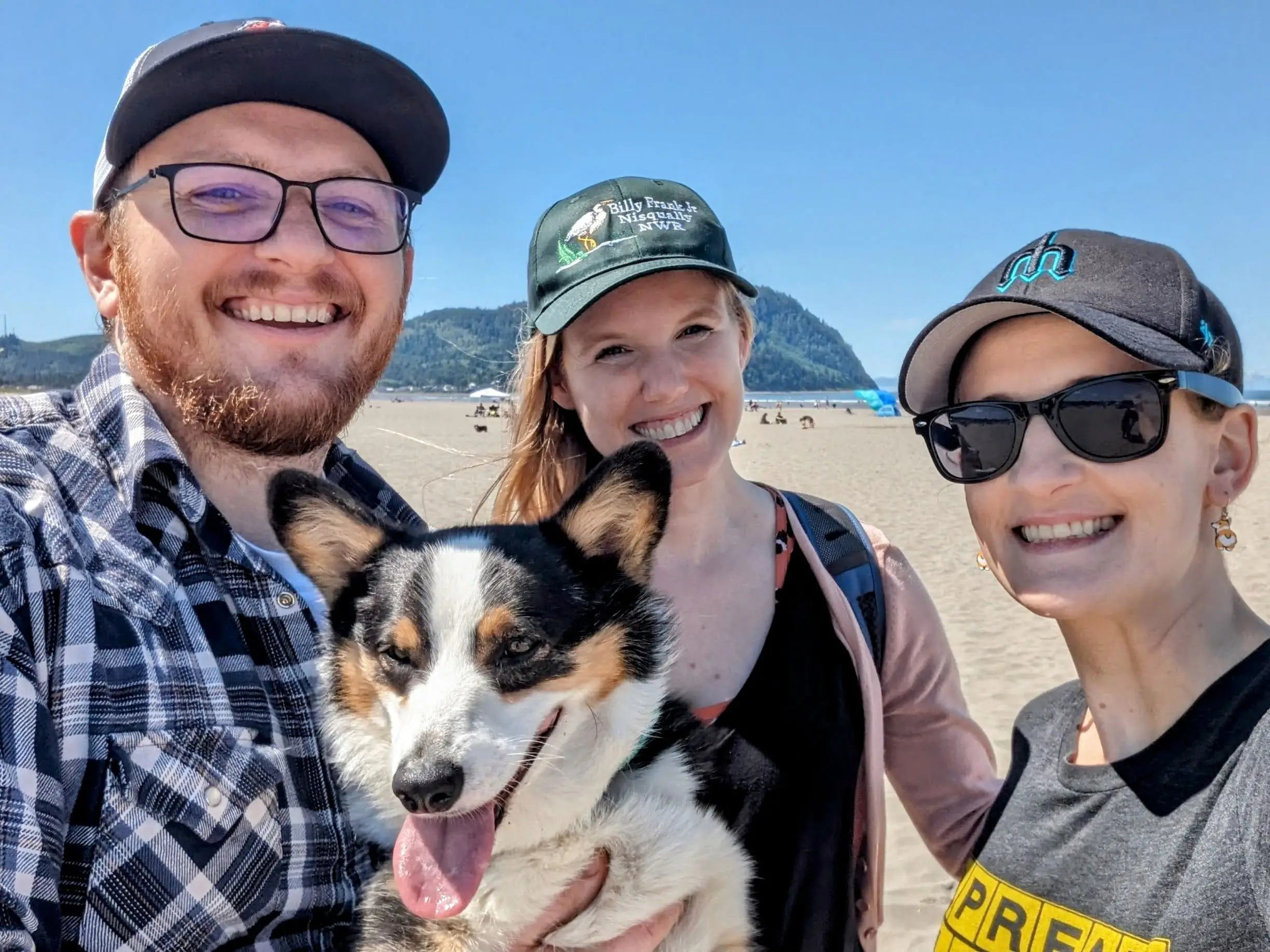 Laura Grace, her husband, and their friend pose for a photo with their dog on the beach.