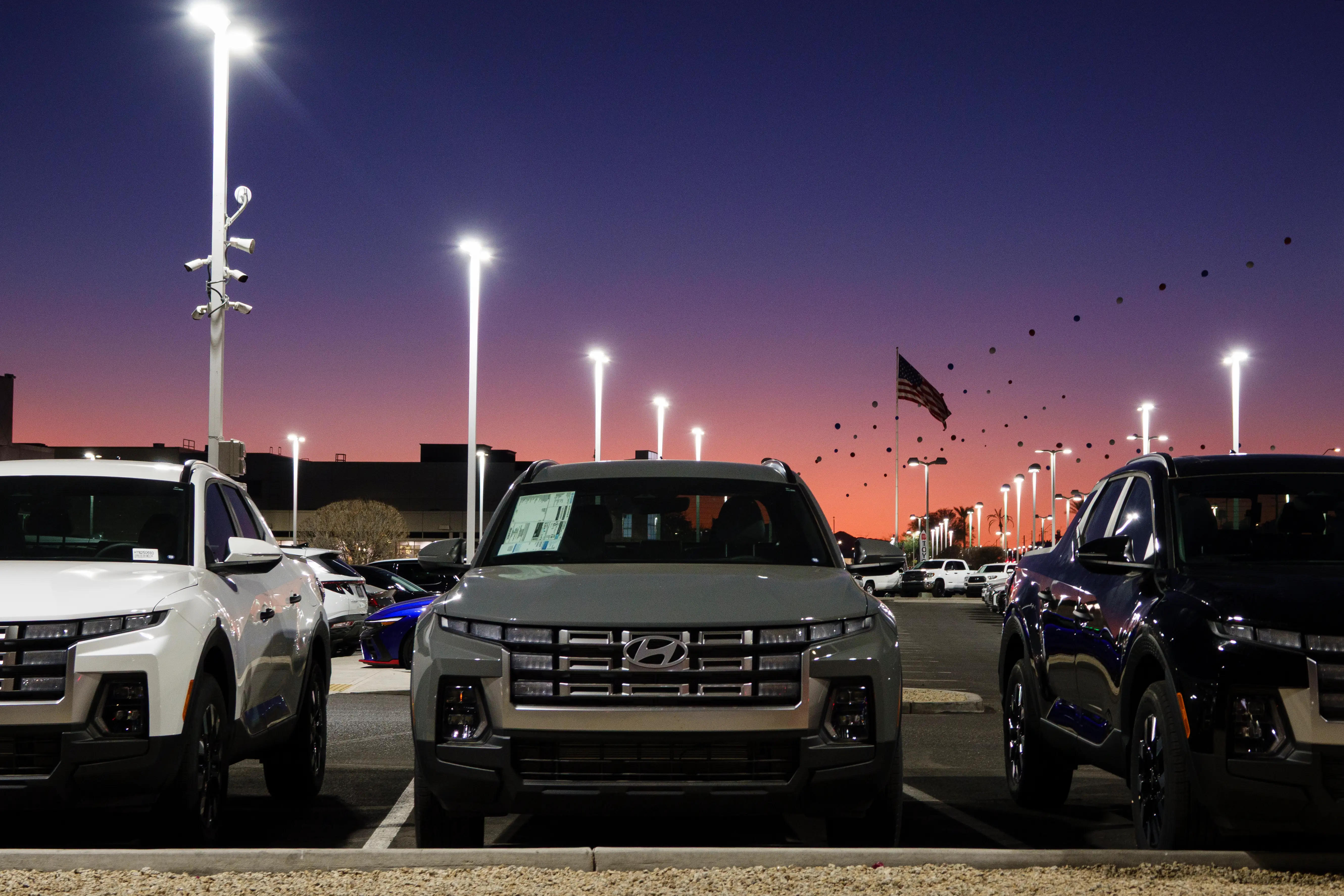 A Hyundai dealership at sunset. There's a row of Santa Cruz pickups.