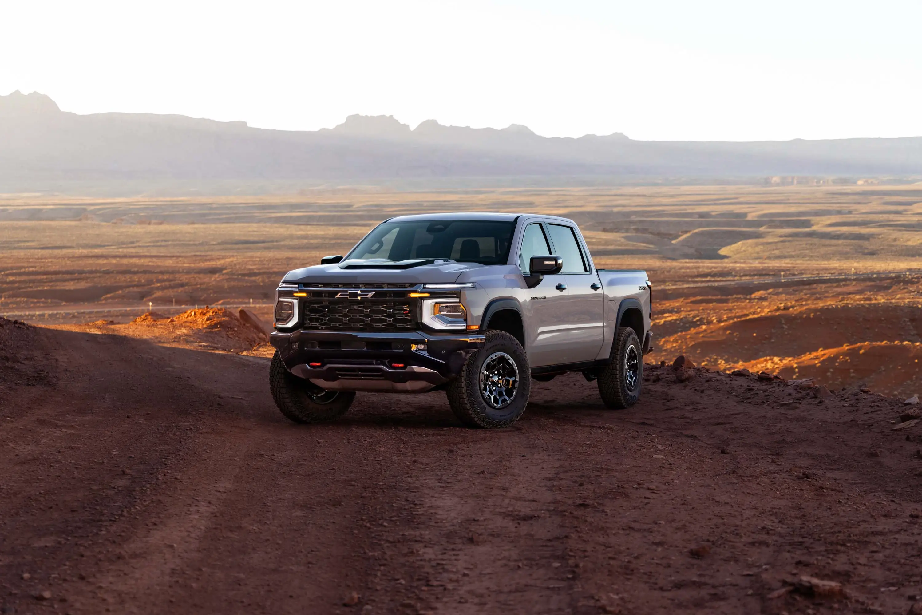 A silver 2027 Chevy Silverado is parked on a dirt path.