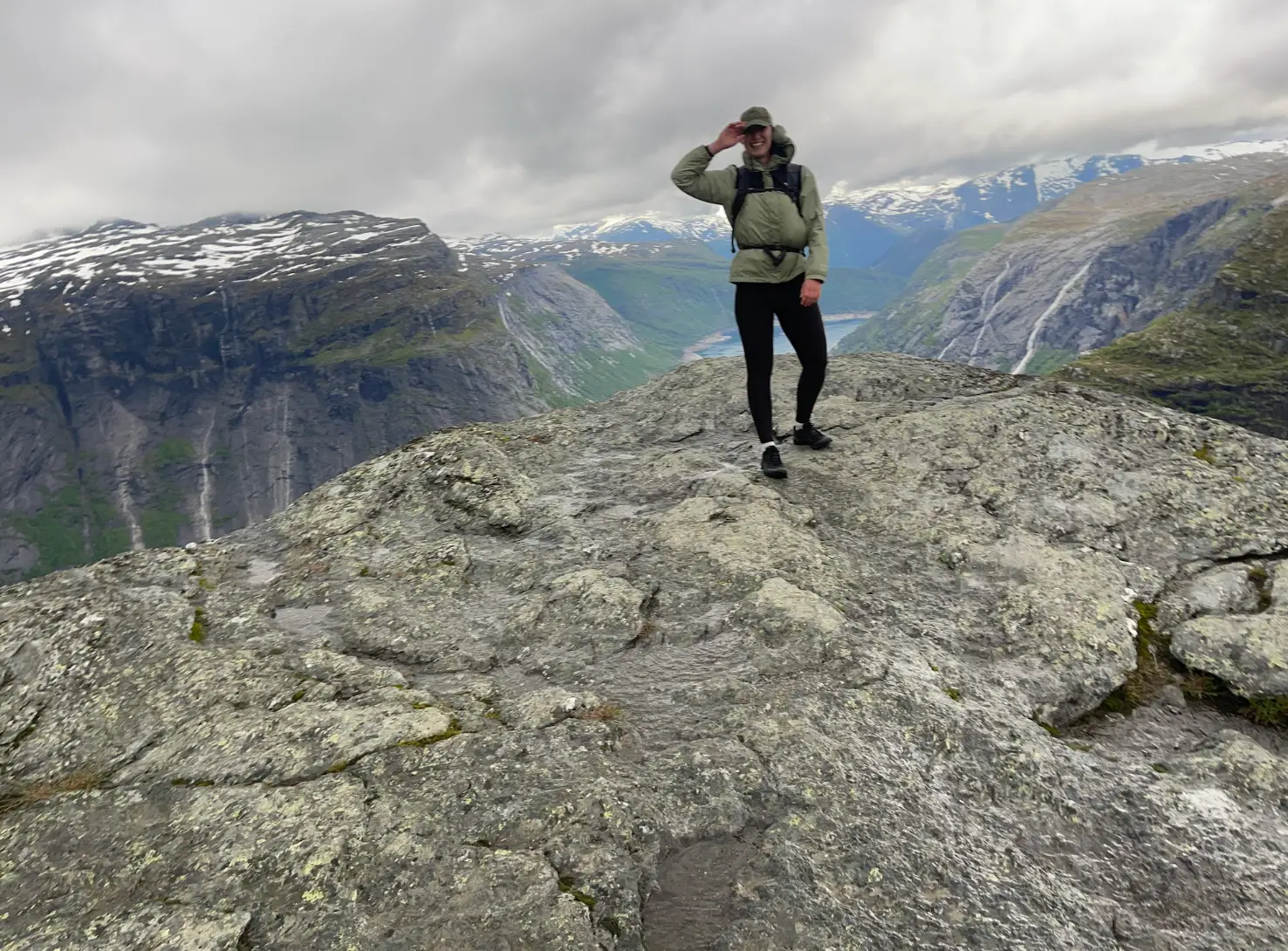 The writer standing on a mountain in Norway, bundled up with snowcapped mountains in the background.