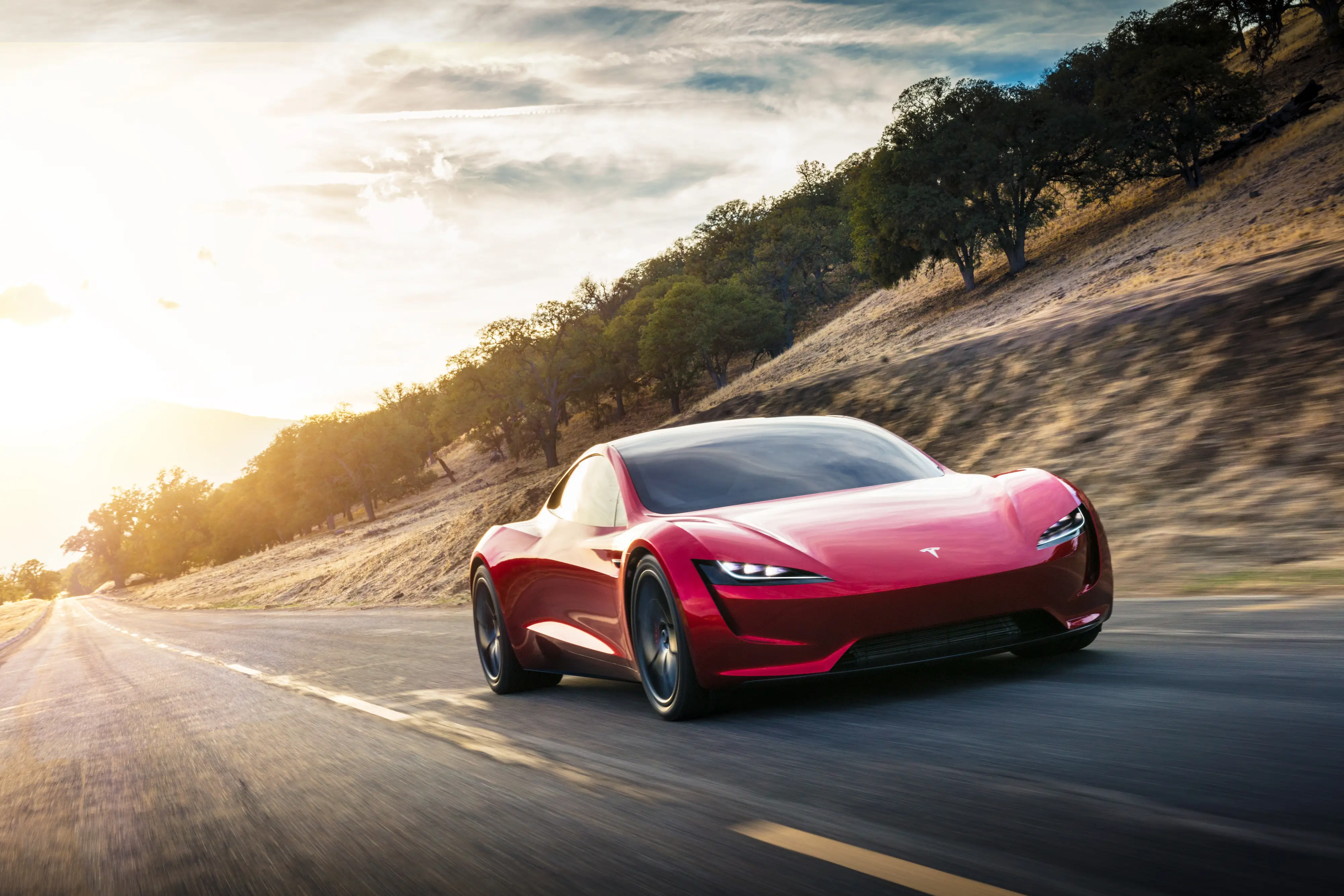 A red Tesla Roadster prototype drives down a two-lane road.