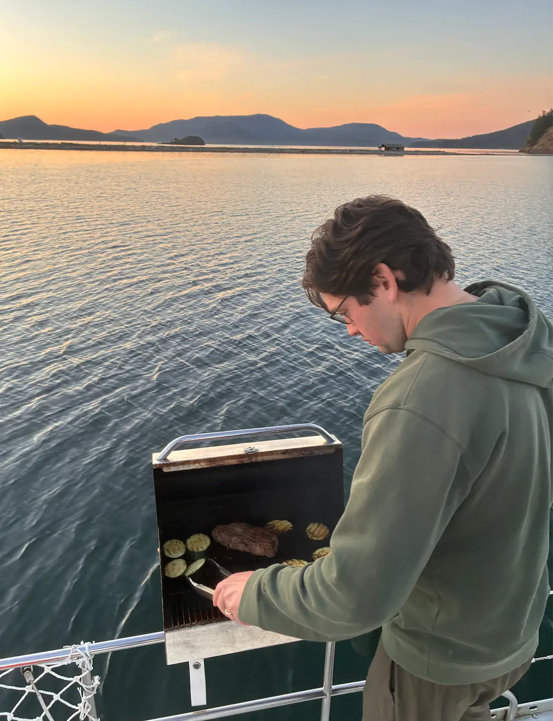 man grills on a sailboat