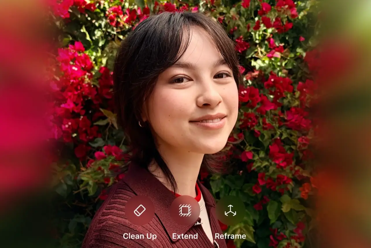 A photograph taken on an iPhone of a woman in front of a wall of red flowers. The left and right sides of the image are blurred.