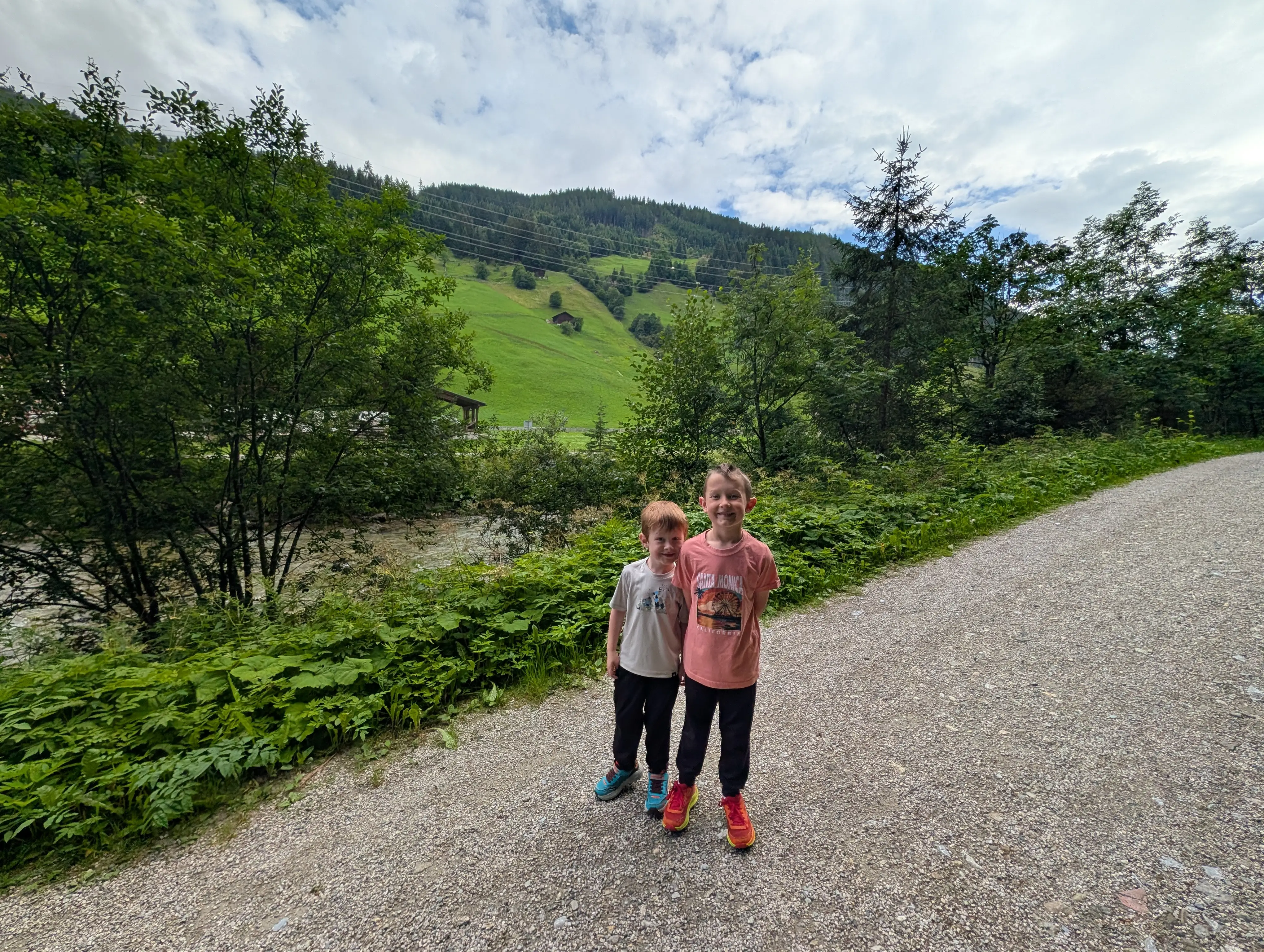 Two buys smiling on hiking trail near trees